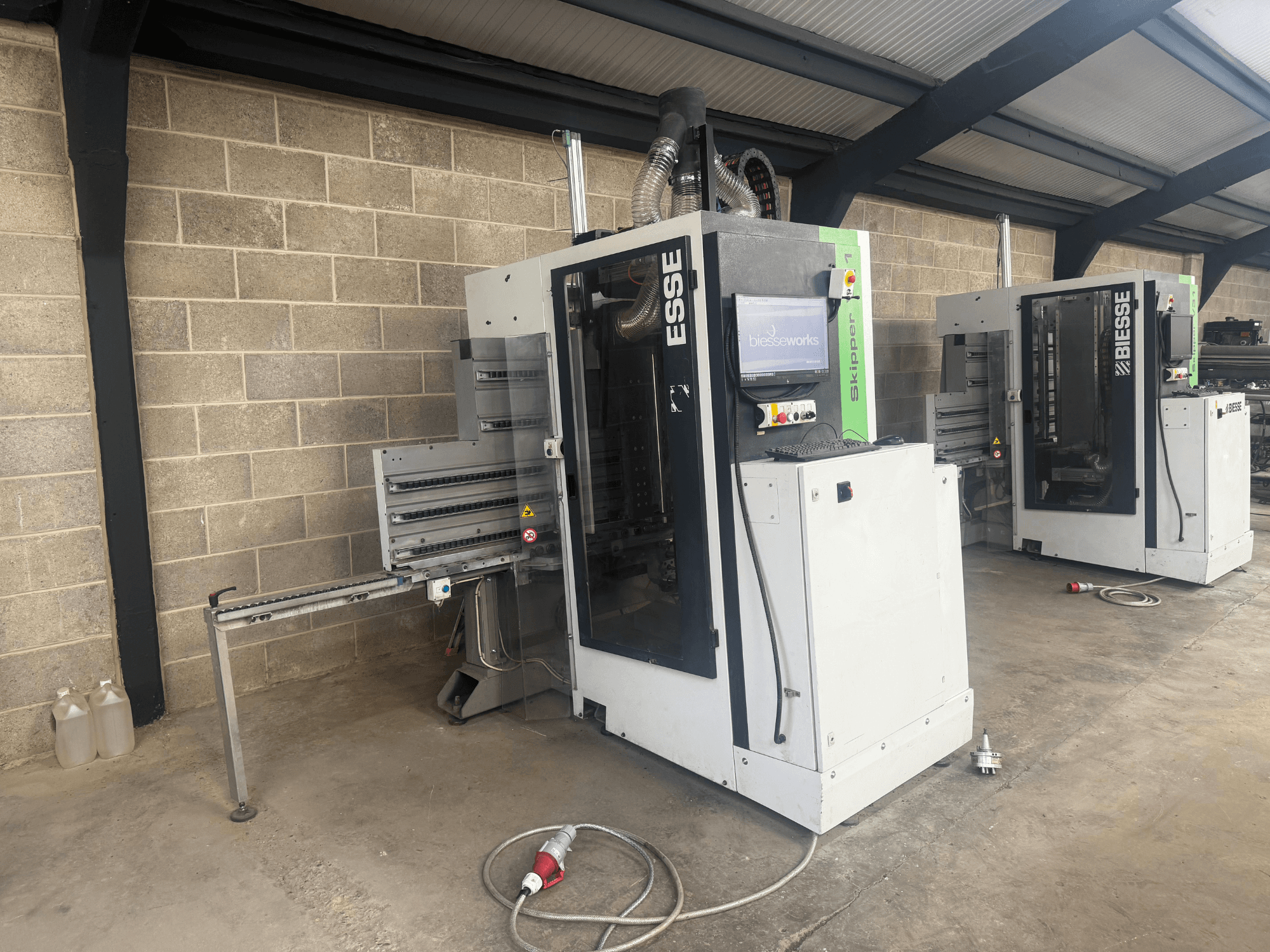 BIESSE Skipper v31 koka urbjmašīna BIESSE Skipper v31 no sāniem, ar vadības paneli un blakus esošajām iekārtām, darbnīcā.