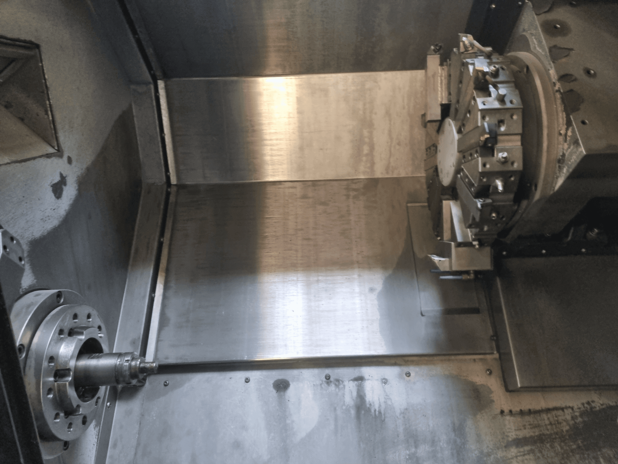 CNC virpas ar rotējošu vārpstu un metāla darba virsmu iekšējais skats, kas demonstrē rūpniecisko precizitāti.