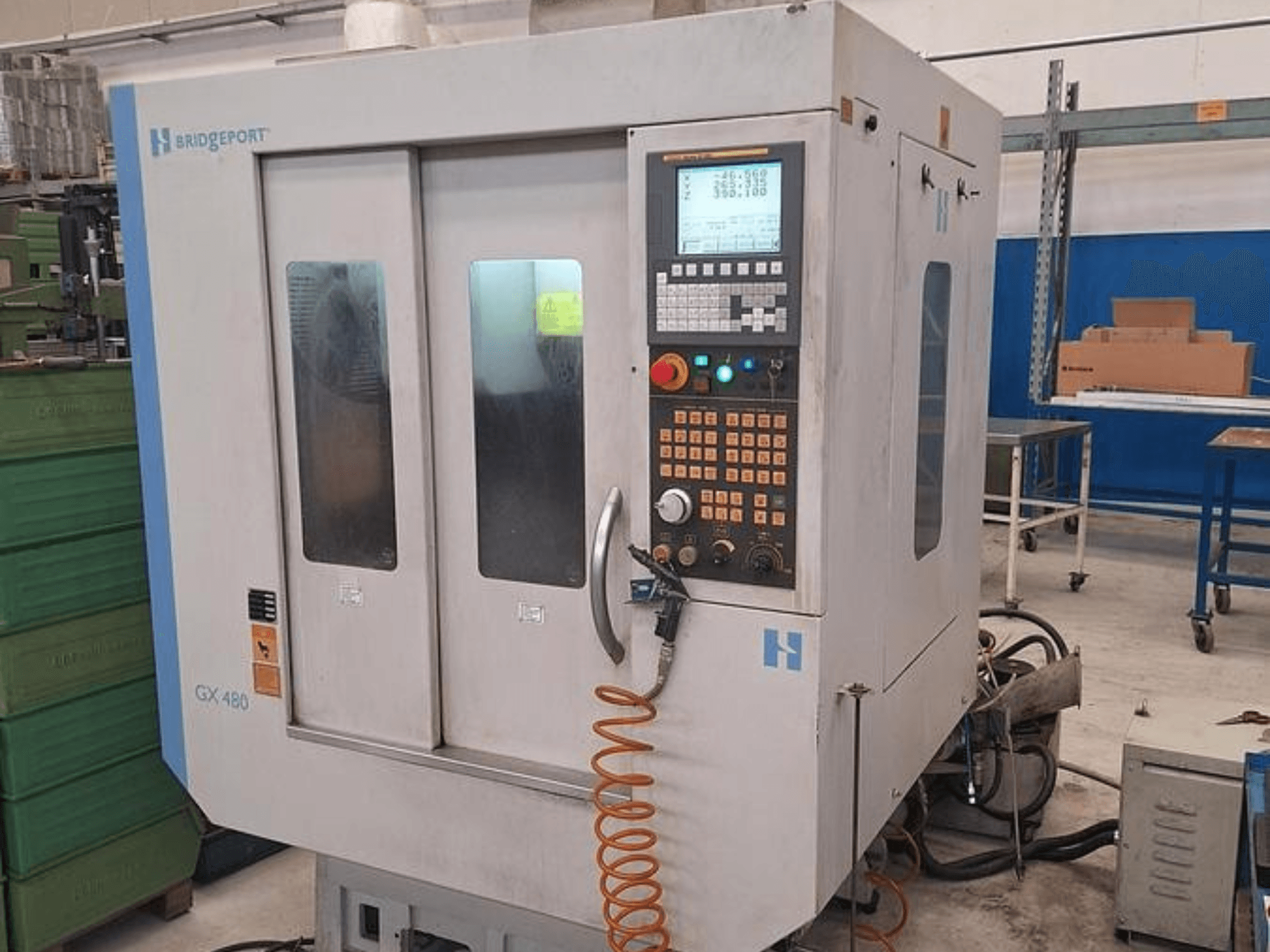 Bridgeport GX 480 vertikālais apstrādes centrs priekšpusē ar vadības paneli, dubultām stikla durvīm un elastīgu šļūteni.