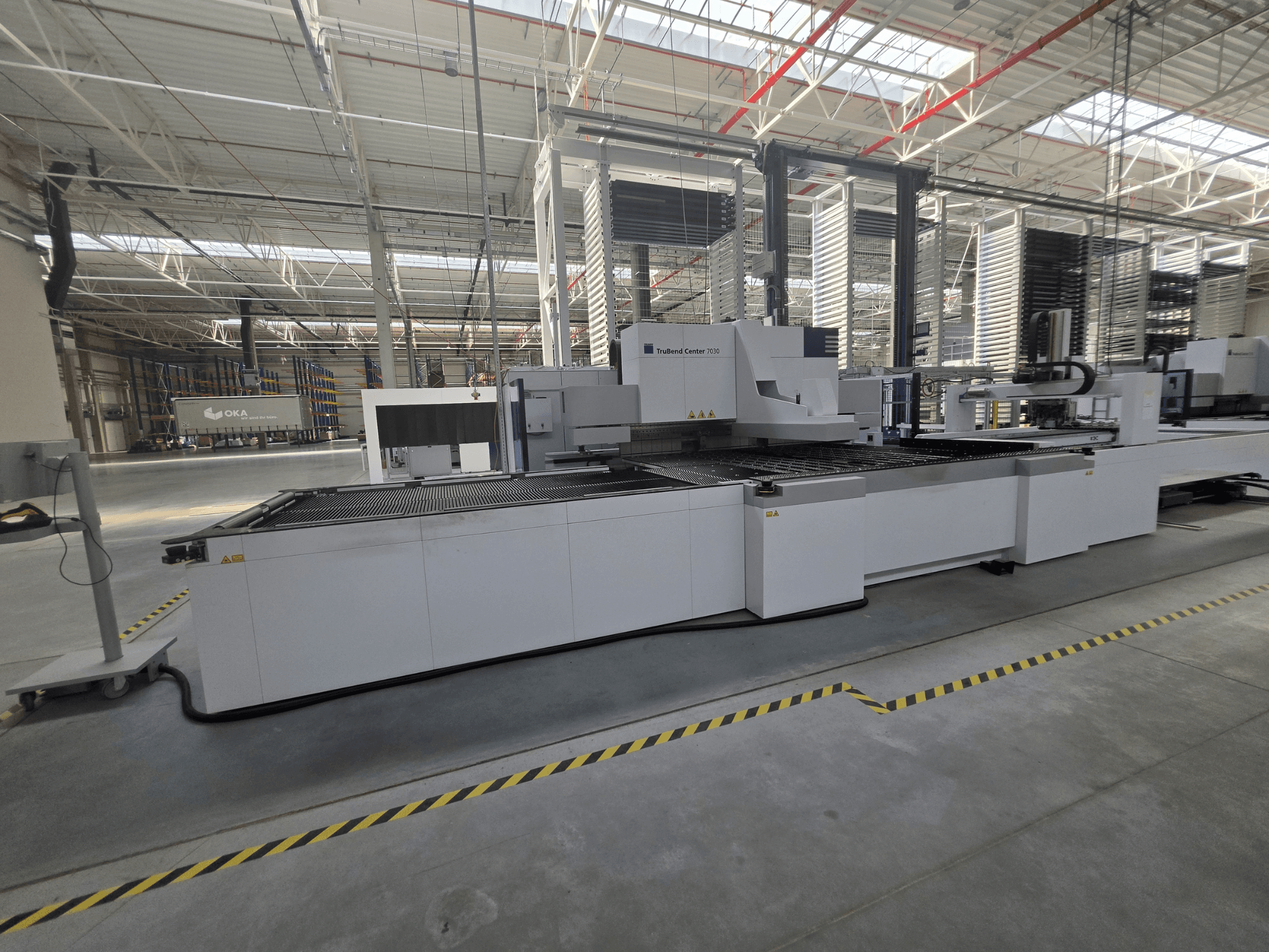 TRUMPF TruBend Center 7030 lieces mašīna, skats no sāniem, kurā redzama darba zona un vadības elementi plašā darbnīcā.