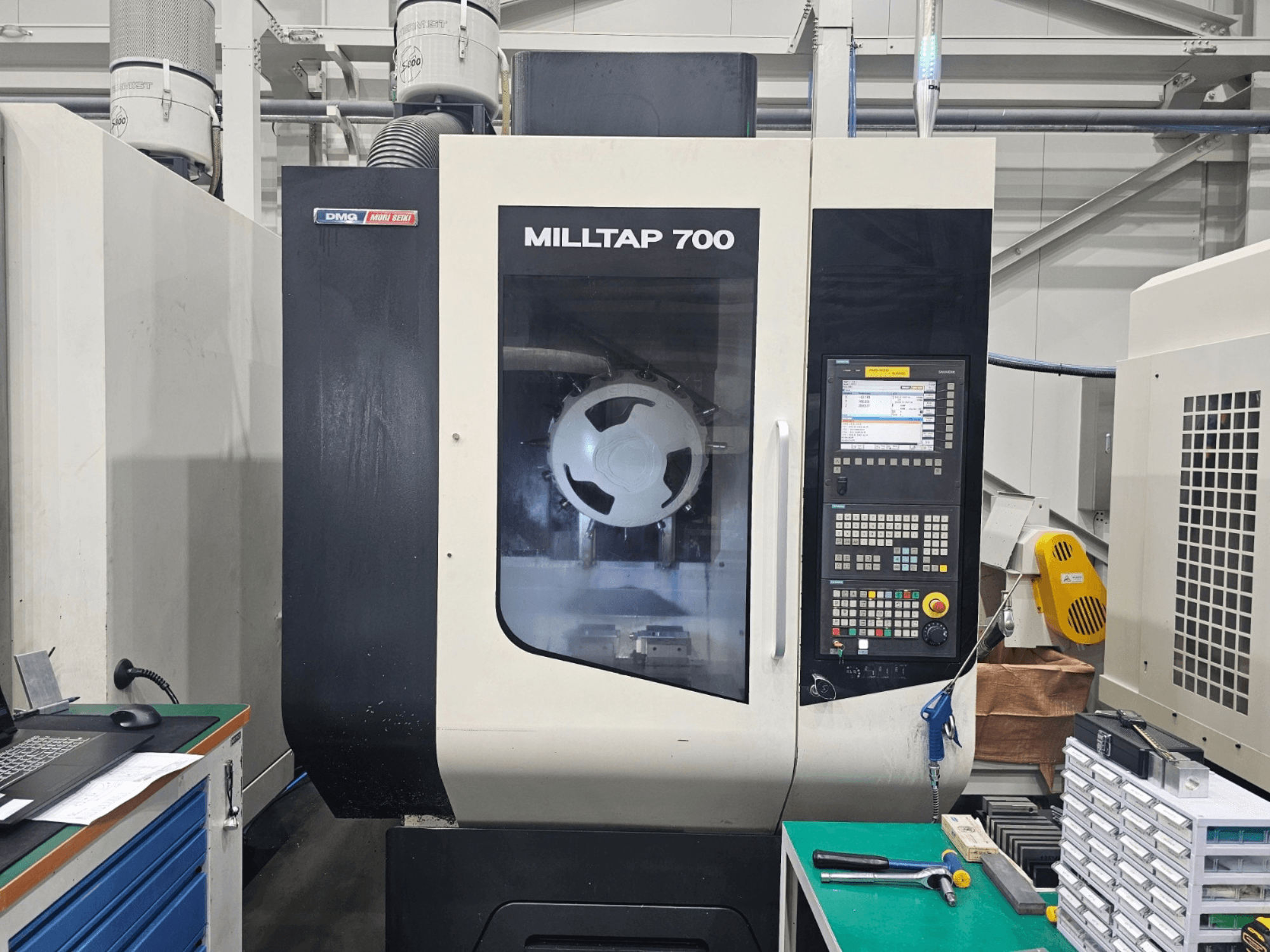 Vertikālais apstrādes centrs DMG MORI MILLTAP 700, skats no priekšpuses, kurā redzams vadības panelis, vārpsta un darba zonas detaļas.