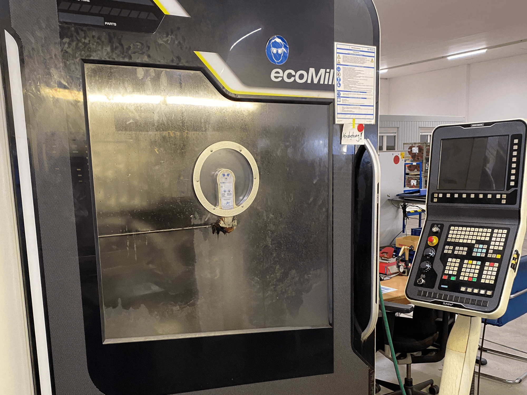 DMG MU 70 ECO frēze, skats no priekšpuses, kurā redzams vadības panelis labajā pusē un stikla paneļis, caur kuru var redzēt iekārtas iekšējās detaļas.