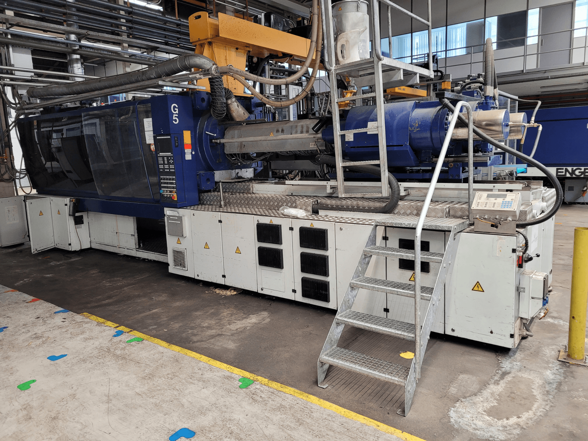 Iesmidzināšanas veidošanas iekārta G5, skats no sāniem, redzams vadības panelis, pakāpienu kāpnes un nerūsējošā tērauda darba virsma.