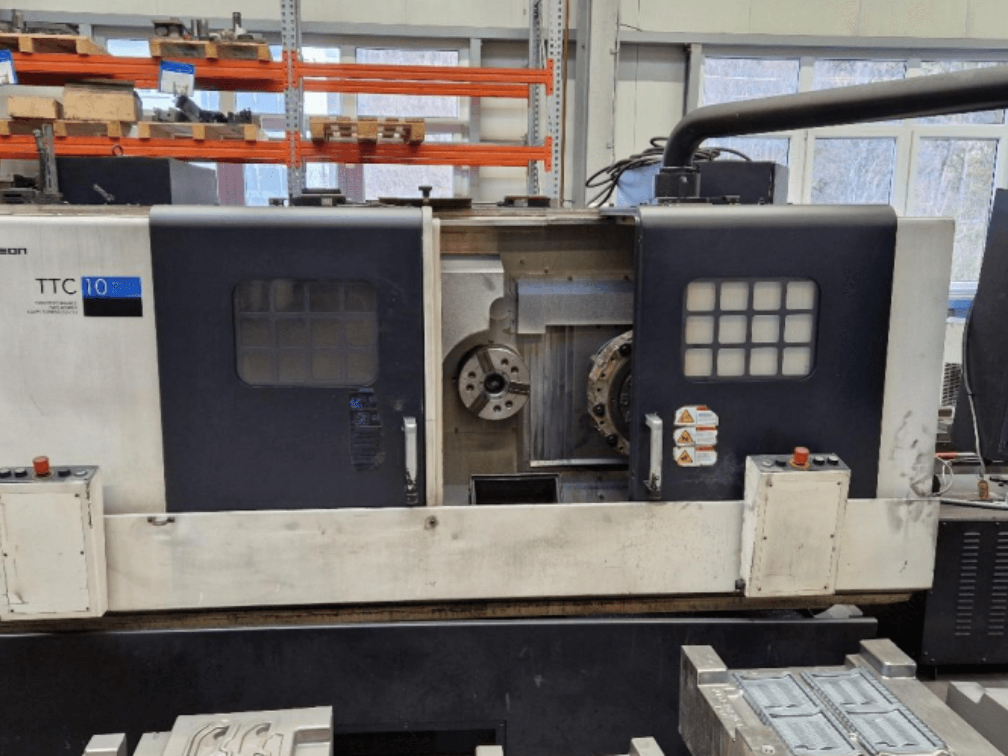 TTC 10 virpošanas mašīnas priekšējais skats, kurā redzams vadības panelis, redzamie turētāji un darba vieta ar metāla detaļām.