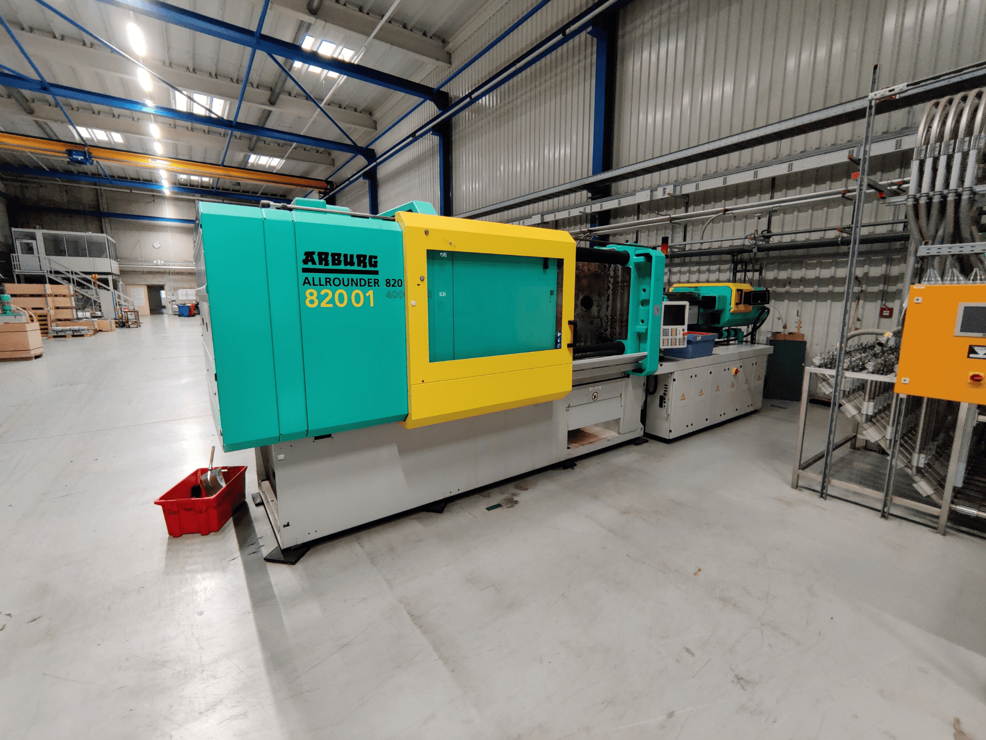 Arburg 820 S 4000-2100 hidrauliskās iesmidzināšanas iekārtas priekšējais skats ar spilgti zaļiem un dzelteniem paneļiem.