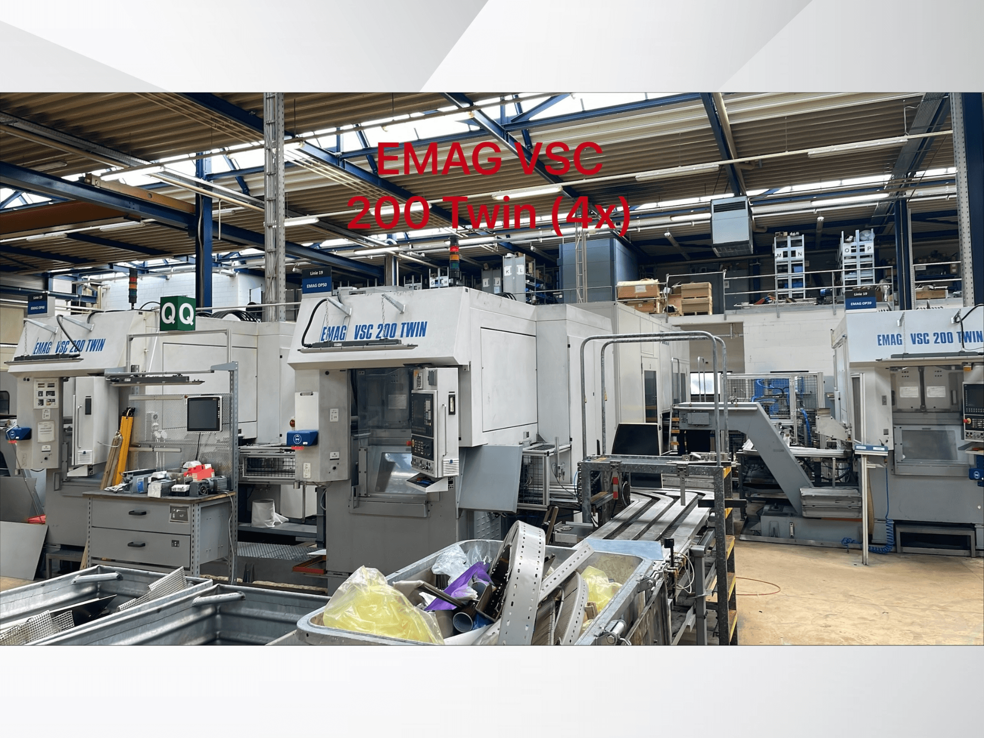 EMAG VSC 200 TWIN OP 20 vertikālās virpošanas darbgaldu priekšējais skats darbnīcā, kurā redzamas vairākas iekārtas un apkārtējais aprīkojums.