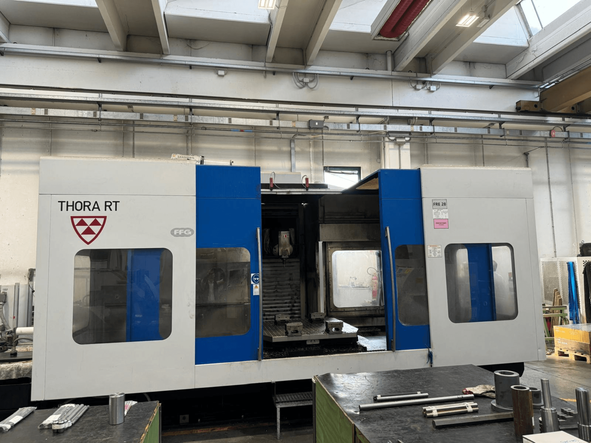 THORA RT CNC darbgalds no priekšpuses ar zili baltu ārējo apdari, caurspīdīgiem logiem un piestiprinātiem instrumentiem.