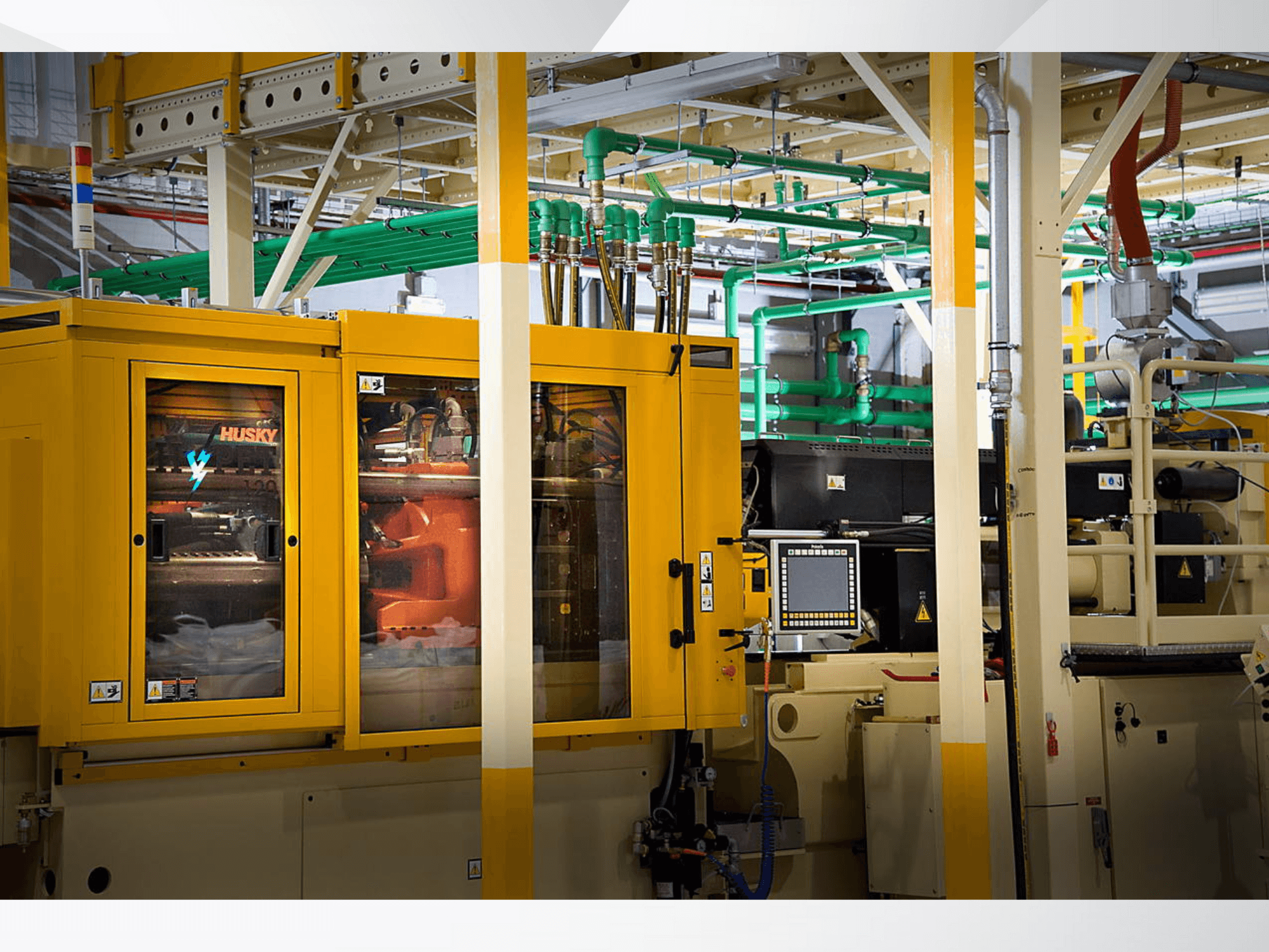 Husky industriālā mašīna dzeltenā krāsā, priekšējais skats uz vadības paneli un iekšējiem mehānismiem uz rūpnīcas fona.