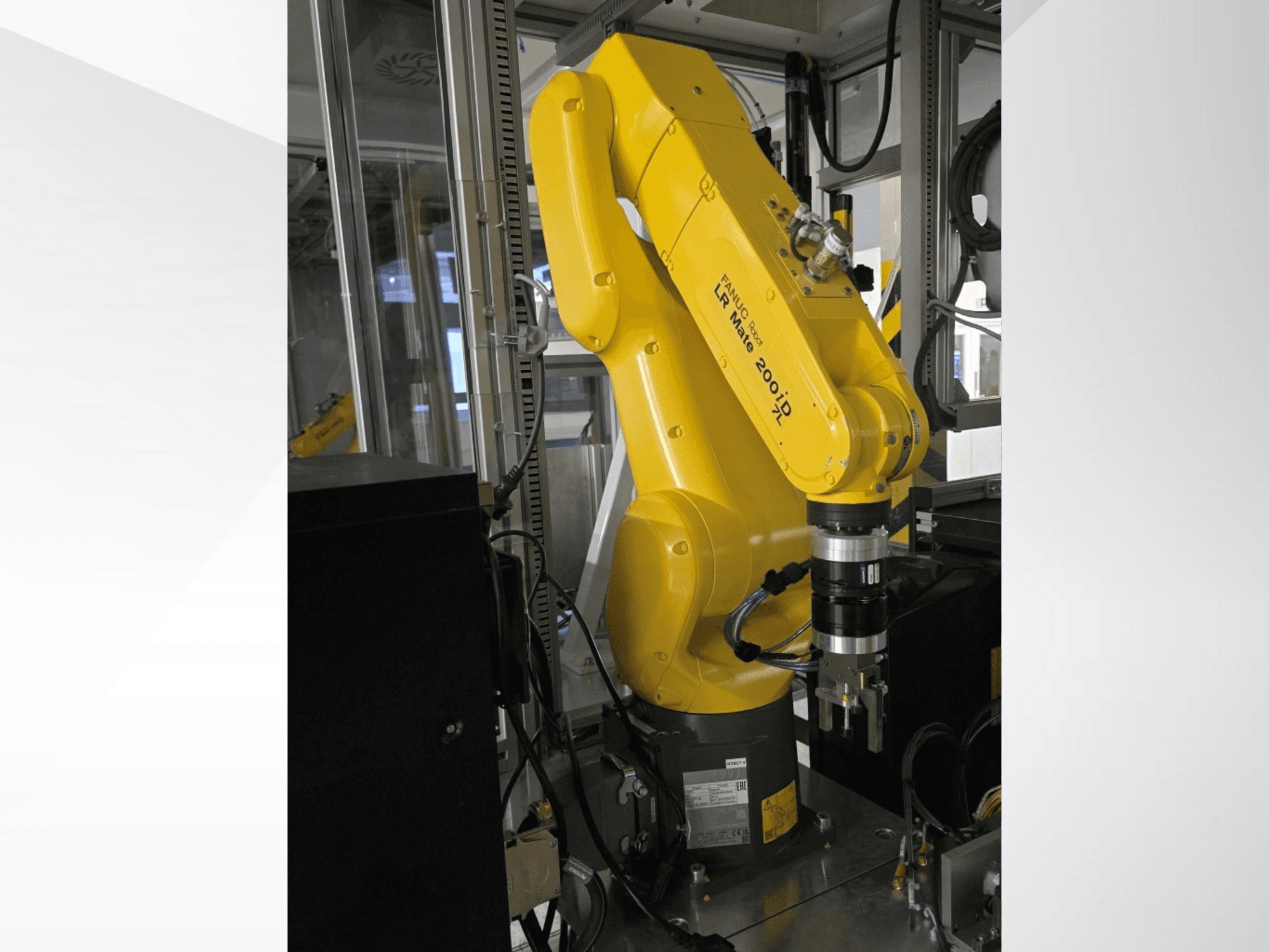 Dzeltenā Fanuc LR Mate 200iD robotizētā roka no sānu skata ar satvērēju un dažādiem pievienotiem kabeļiem.