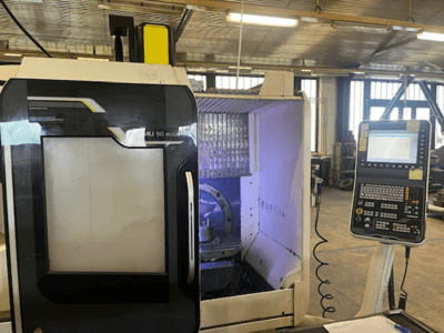 DMU 50 eco frēzmašīnas priekšējais skats ar vadības paneli, instrumentu turētāju un darba vietu.