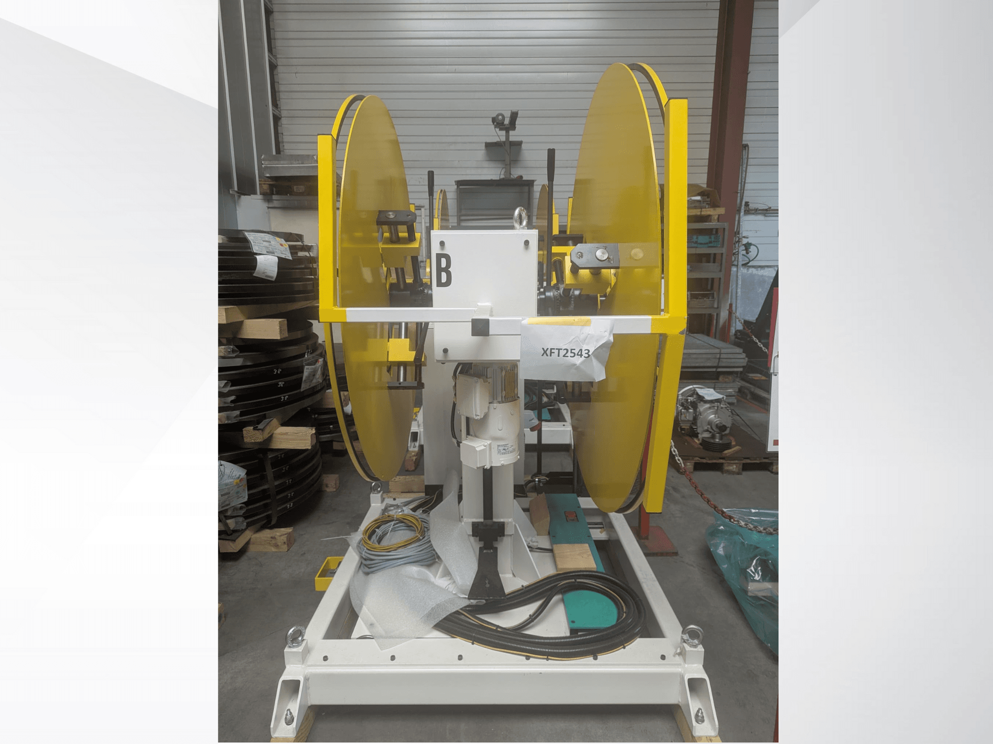 Dzelteni ripzāģa diski, kas uzstādīti uz baltas mašīnas pamatnes, skats no priekšpuses; modelis XFT2543, ar redzamiem vadiem un komponentiem.