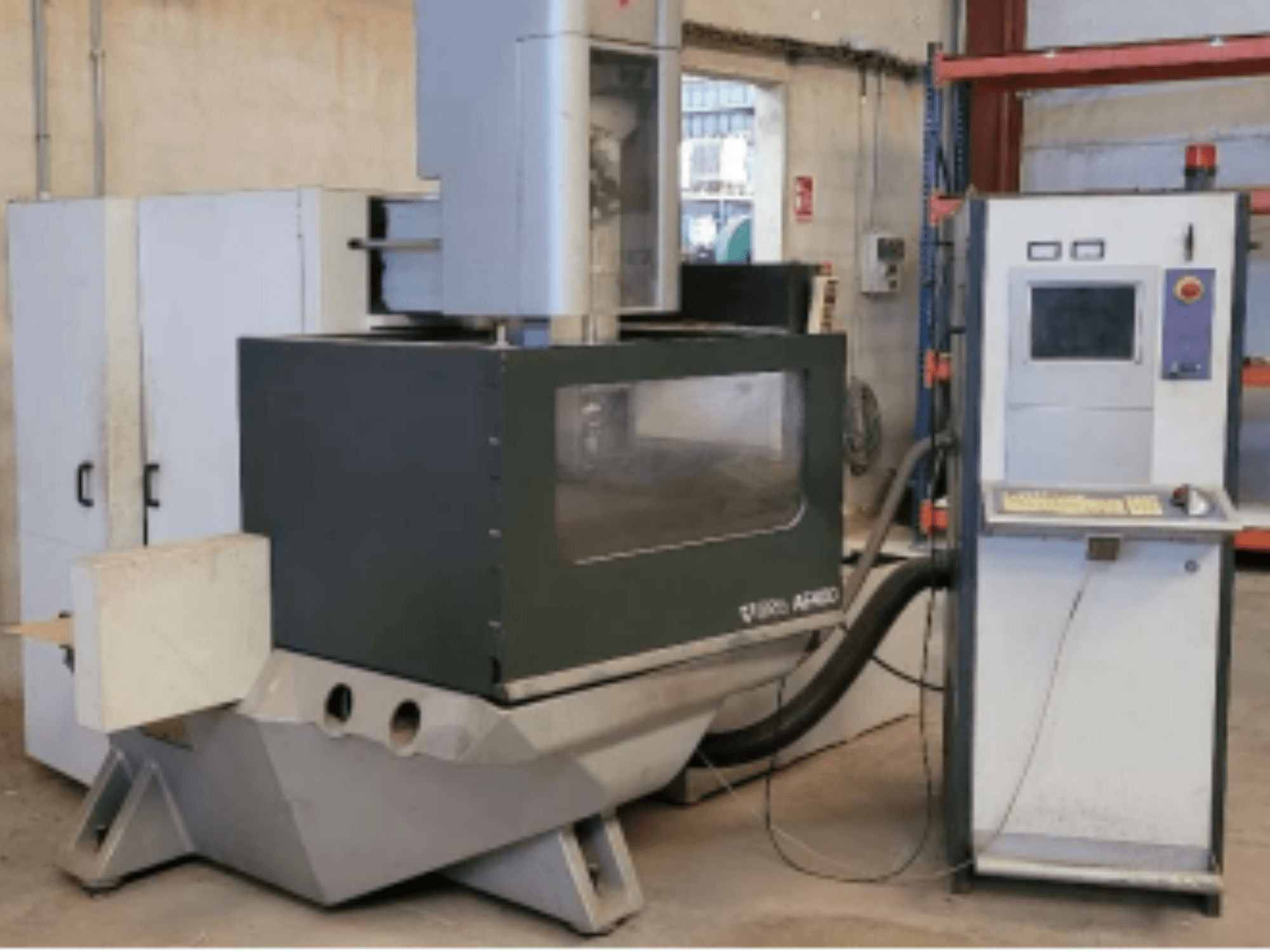 ONA AE 400 stiepļu EDM mašīna darbnīcā, ar vadības paneli labajā pusē un lielu griešanas laukumu.