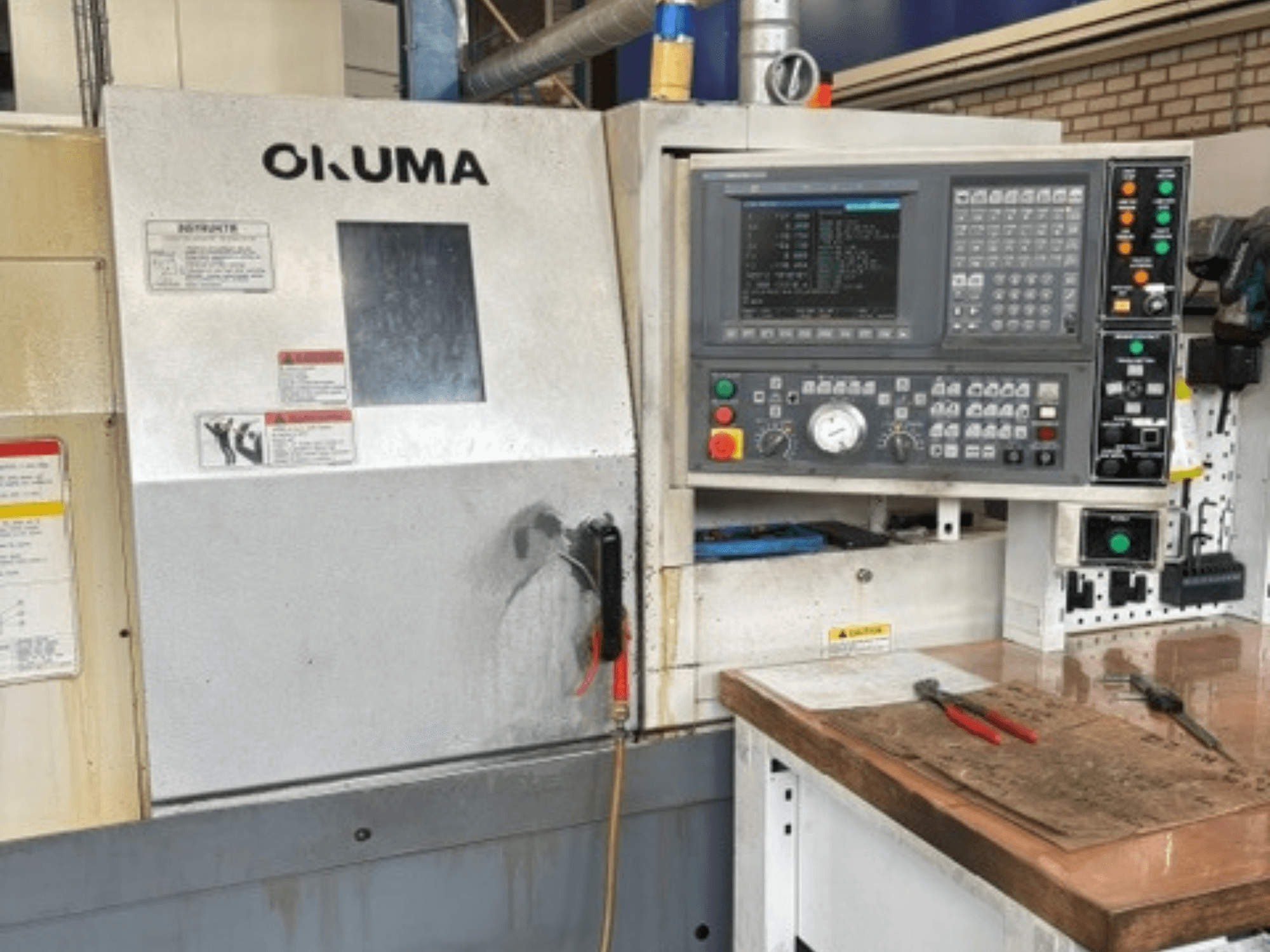 Okuma ES-L10II horizontālās virpošanas mašīnas skats no priekšpuses, kurā redzams vadības panelis, displejs un darba zona ar instrumentiem.