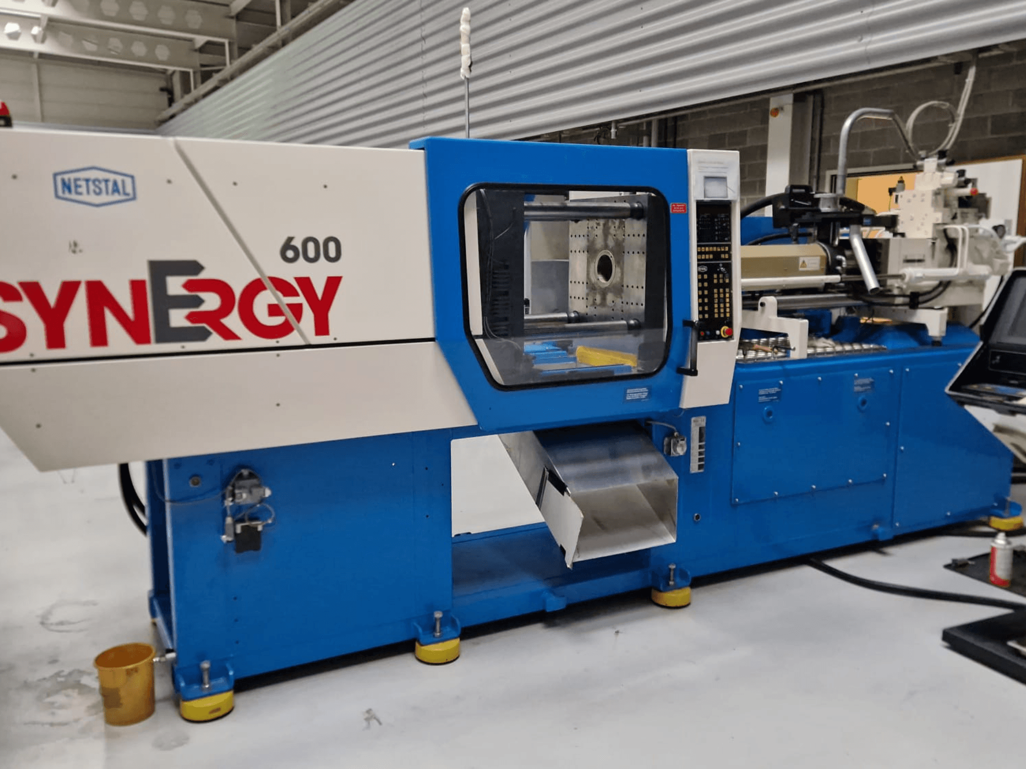 Netstal Synergy 600-230 hidrauliskā iesmidzināšanas iekārta, sānu skats, kurā redzams vadības panelis un iesmidzināšanas zona.