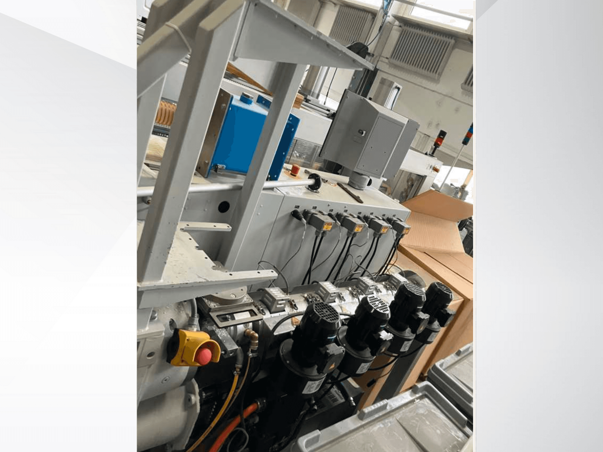 Rūpniecisko iekārtu vadības panelis ar vairākiem motoriem, mērinstrumentiem un monitoru; skats no sāniem rūpnīcā.