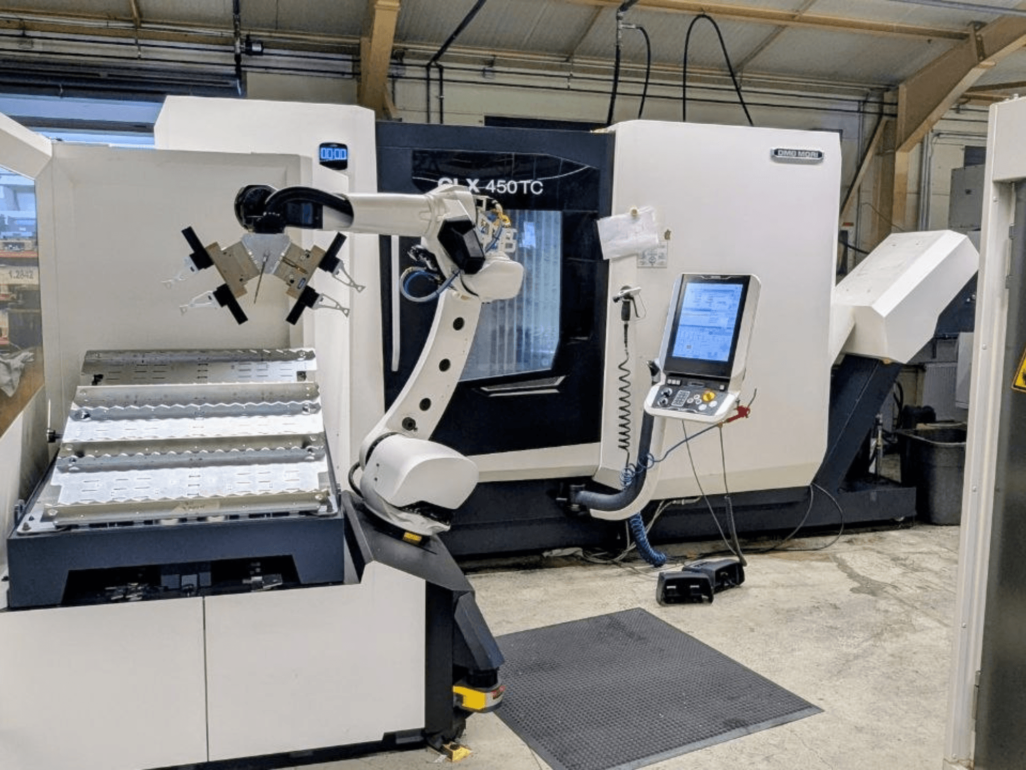 DMG MORI CLX 450 TC ar Robo2go, skats no priekšpuses, kurā redzama robota roka un vadības panelis blakus mašīnai.