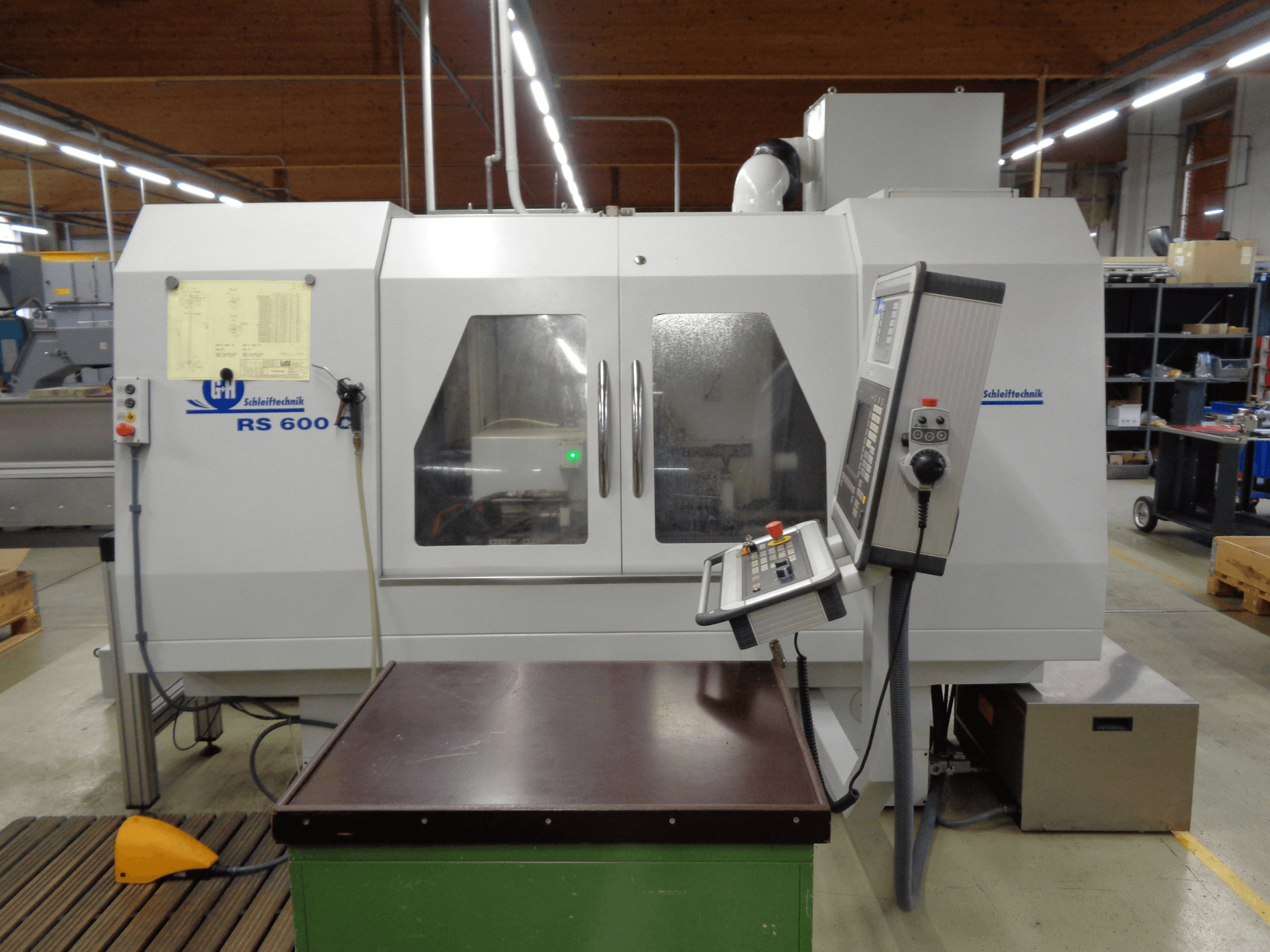 Cilindriskās slīpmašīnas GEIBEL & HOTZ RS 600 C, priekšējais skats, kurā redzams vadības panelis un darba galds rūpnīcā.