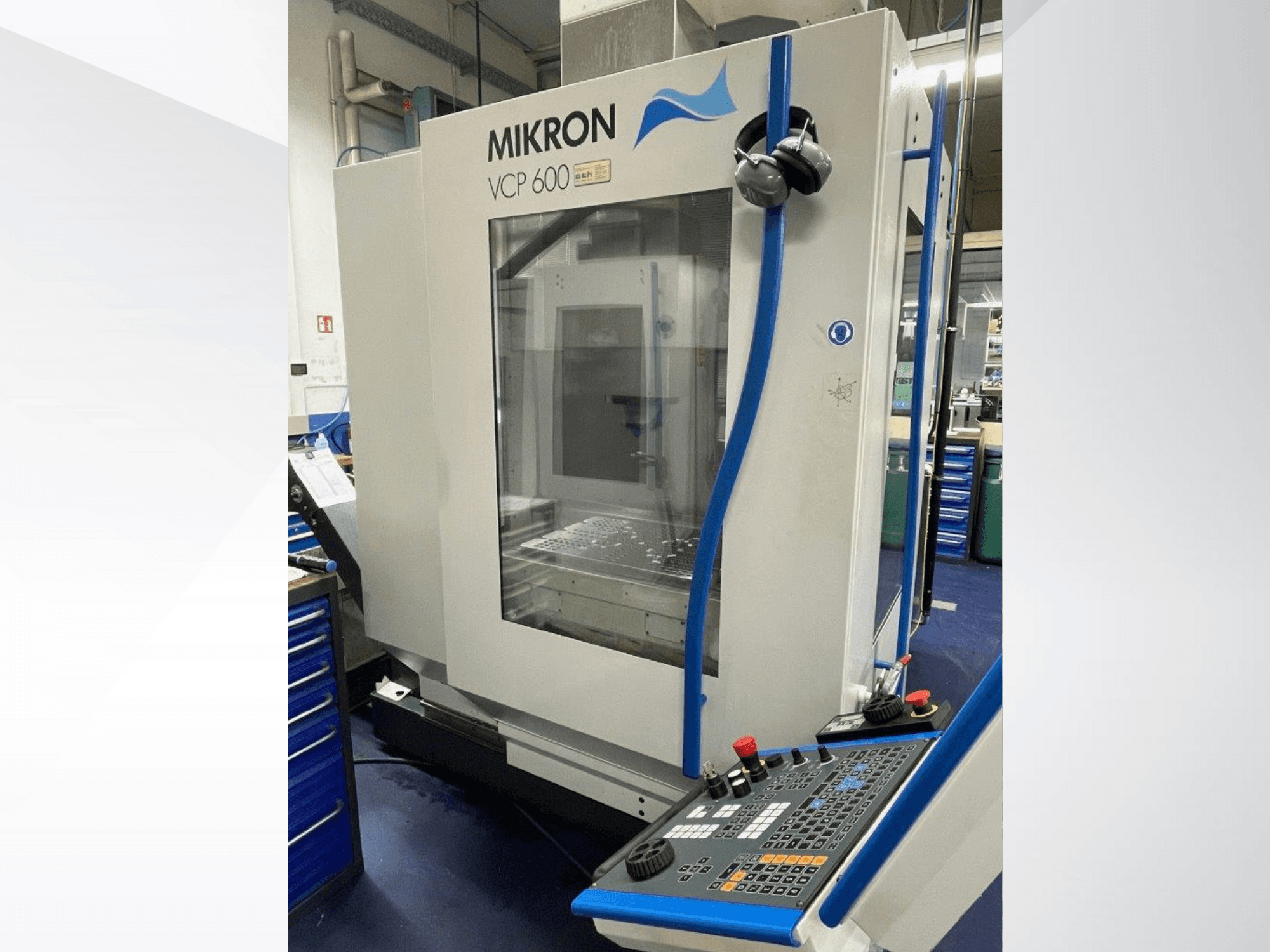 Mikron VCP 600 apstrādes centrs darbnīcā, skats no priekšpuses, ar vadības paneli ar pogām un slēdžiem.