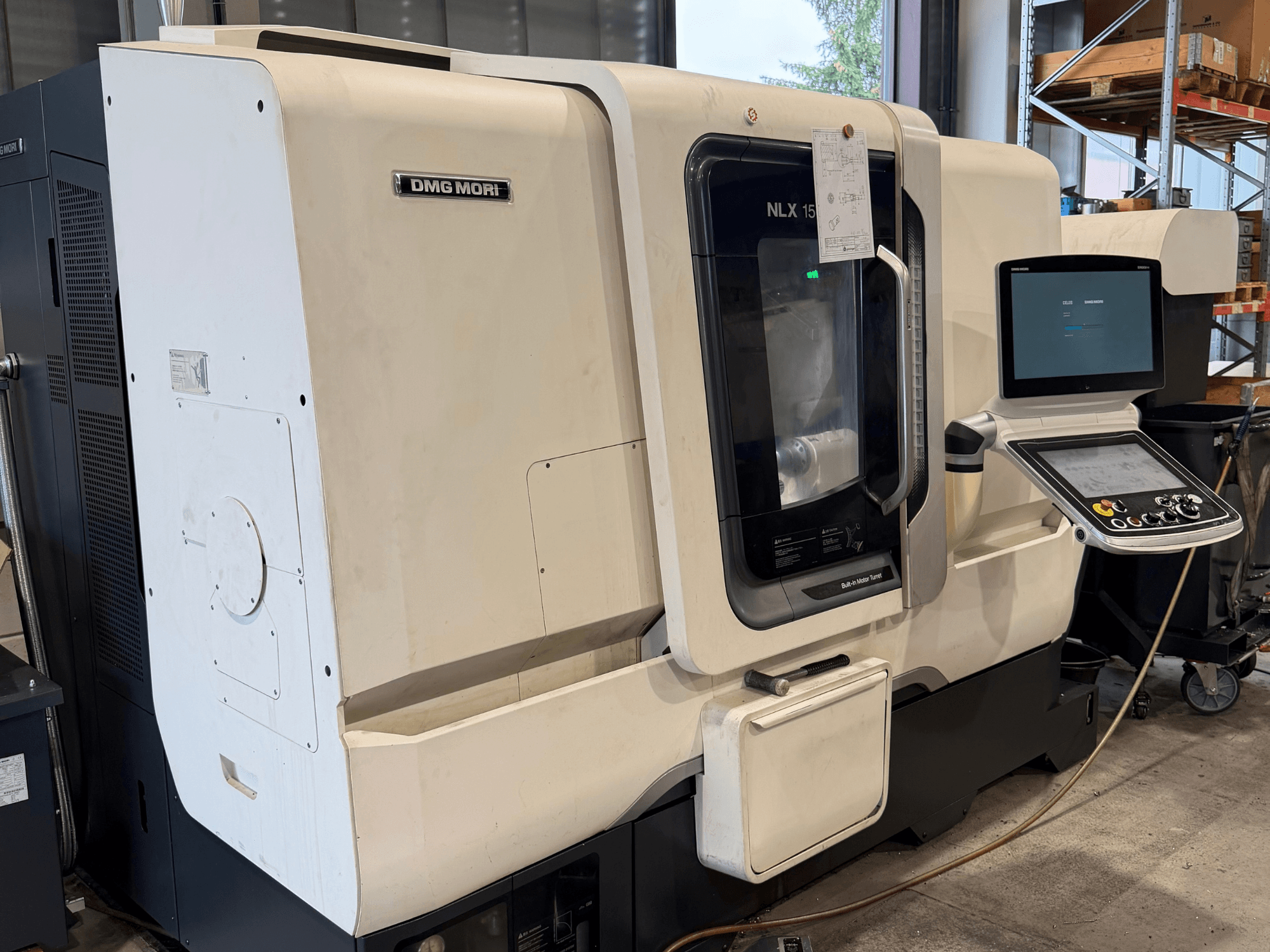 DMG MORI NLX1500MC/500 horizontālās virpošanas mašīnas skats no priekšpuses, kurā caur caurspīdīgo vāku redzams vadības panelis un vārpstas zona.