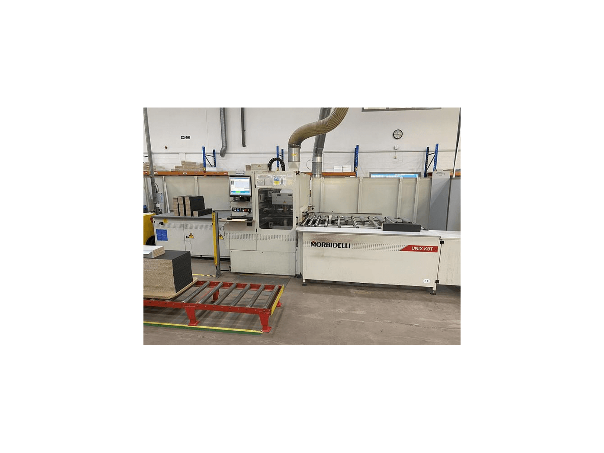 MORbidelli Unix KBT paneļu zāģis, skats no priekšpuses, ar redzamu vadības paneli un uz blakus esošā ratiņa sakrautiem dēļiem.