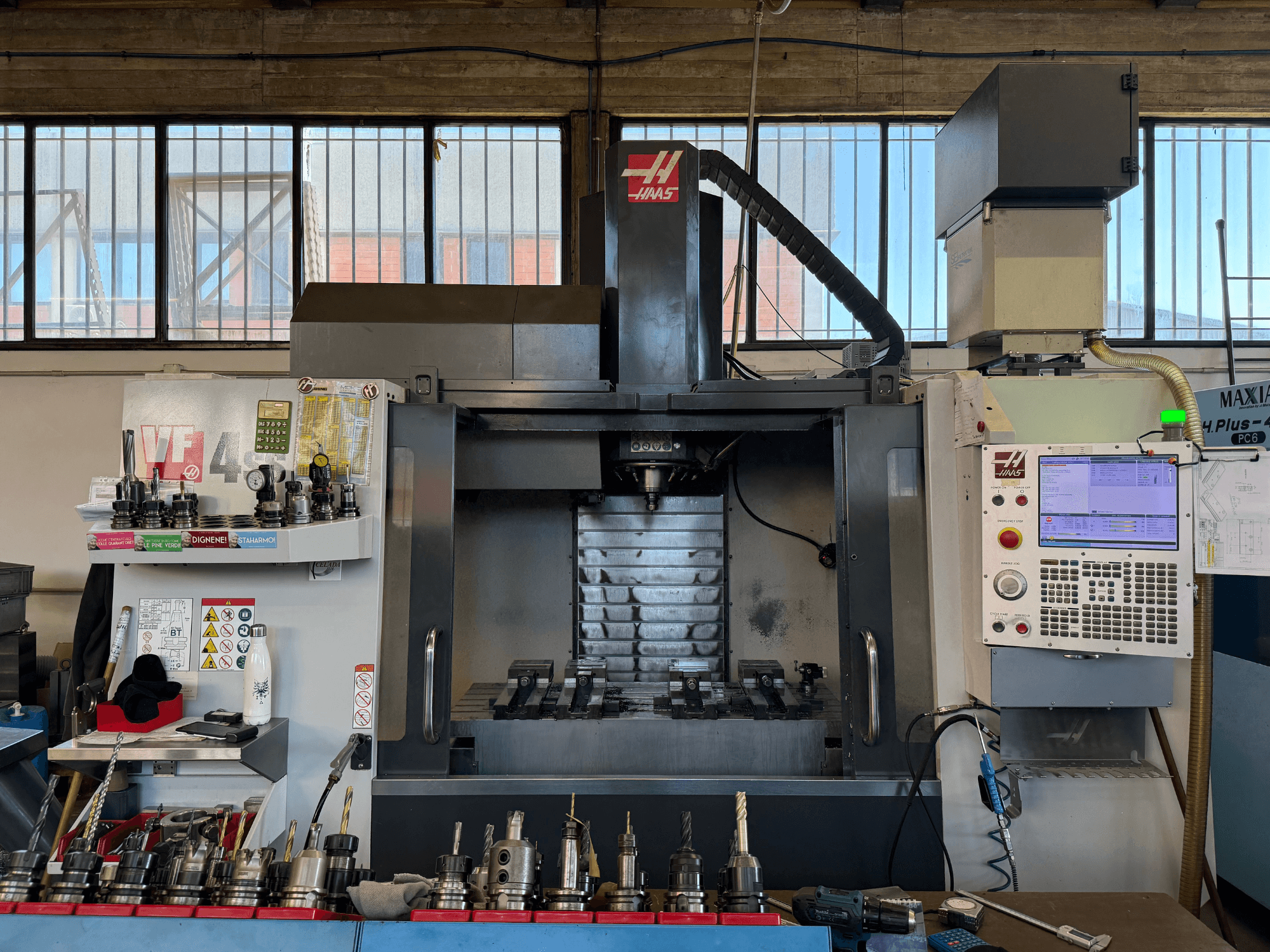 HAAS VF-4SS vertikālais apstrādes centrs, skats no priekšpuses, kurā redzams vadības panelis, instrumentu turētāji un vārpstas zona.