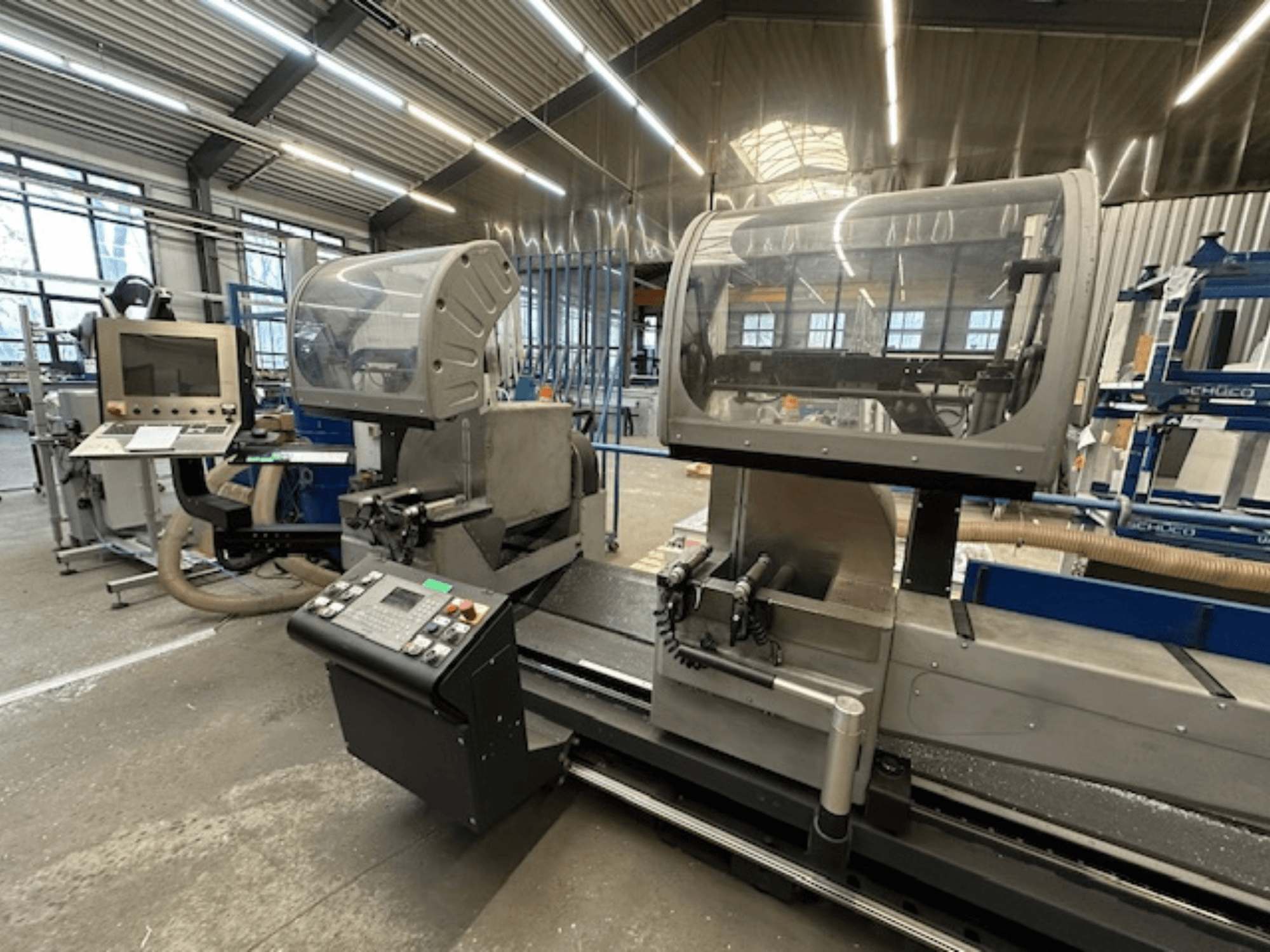 Ripzāģis metālam SCHÜCO PDG E CUT, skats no priekšpuses, ar vadības paneli, aizsargvāciņiem un griešanas zonu darbnīcā.