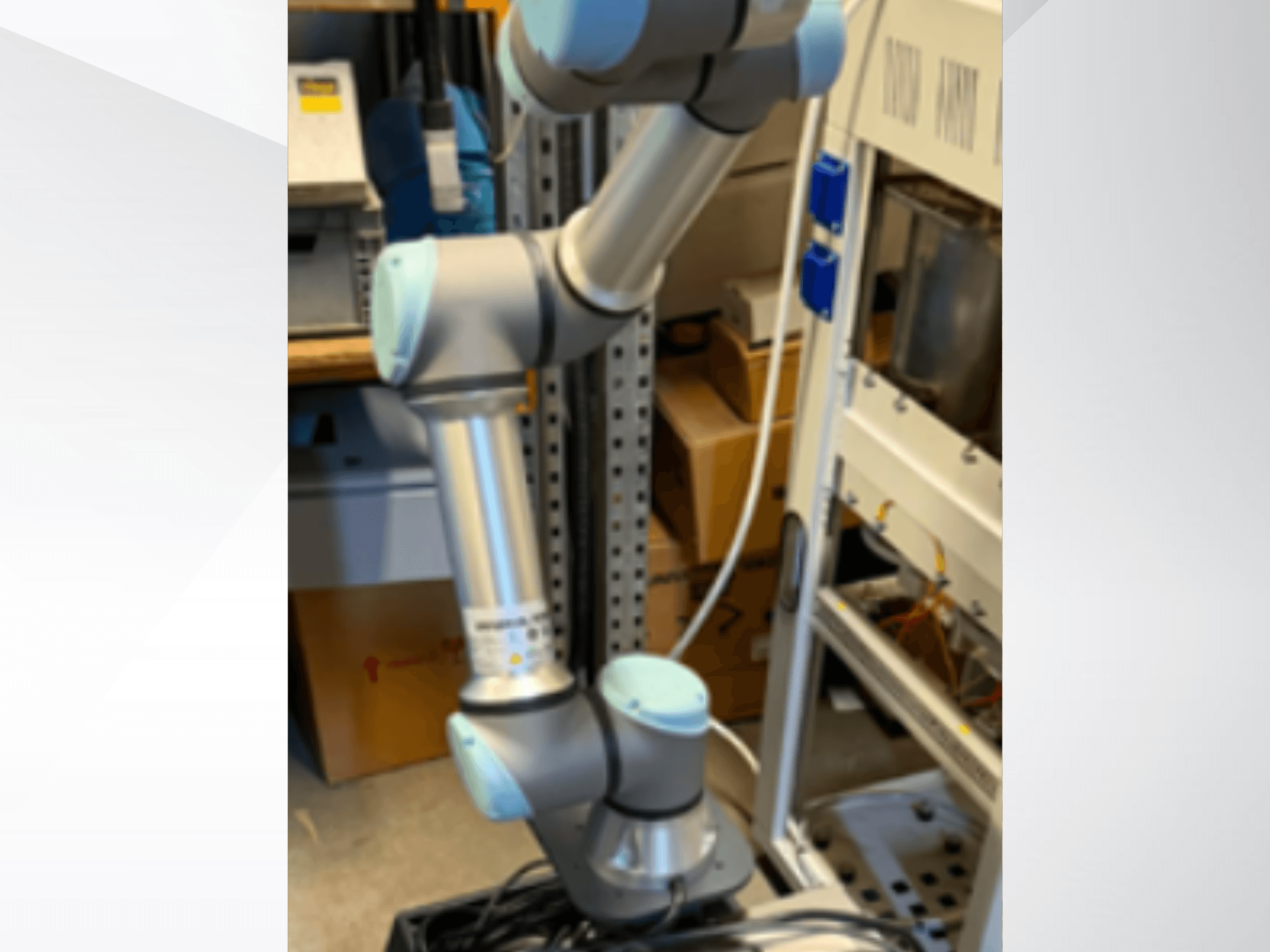 Universal Robots UR5e robota roka, skatīta no sāniem, kurā redzami šarnīrveida savienojumi, vieglā konstrukcija un vadības kabeļi.