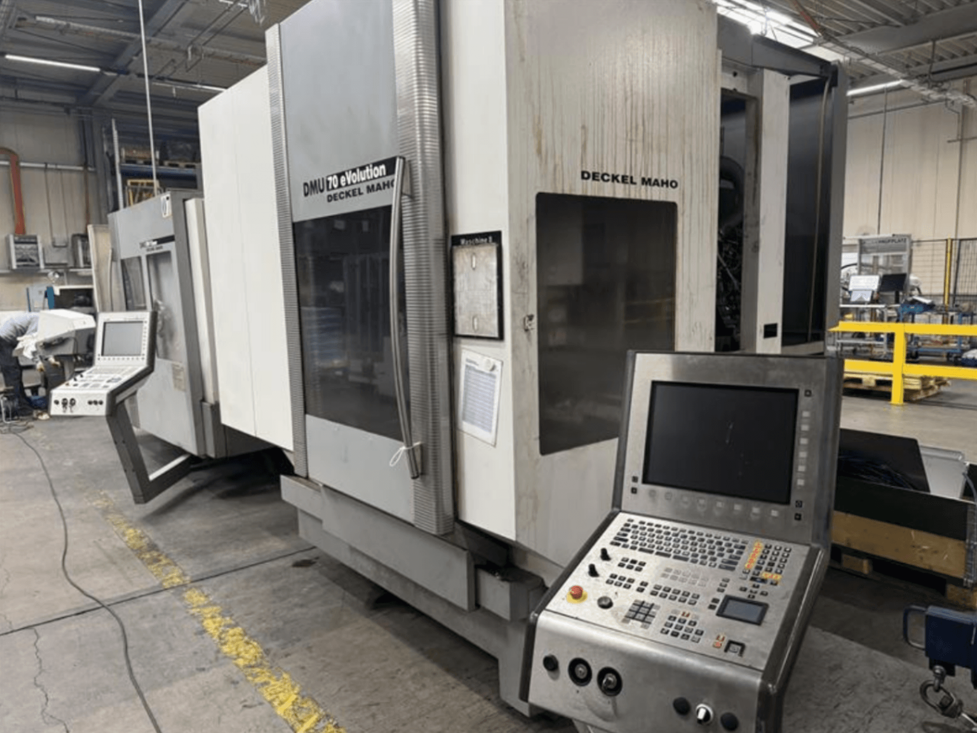 Deckel Maho DMU 70 eVOLUTION eVOLUTION CNC mašīnas ar vadības paneli priekšējais skats, kas atrodas ražošanas uzņēmumā.