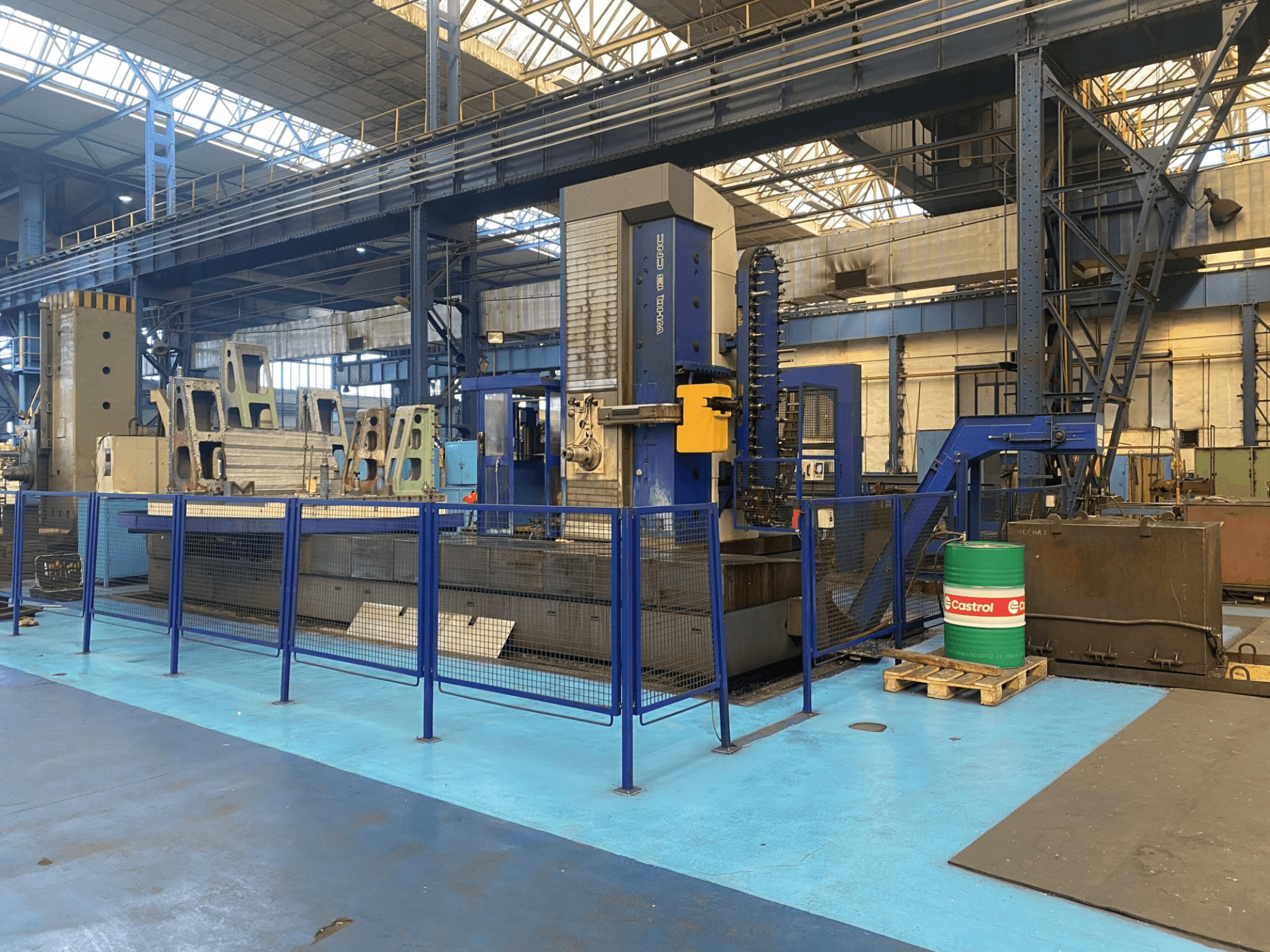 TOS WHQ 13 CNC urbjmašīna darbnīcā, skats no priekšpuses, redzams zilais rāmis un apkārt esošais drošības žogs.