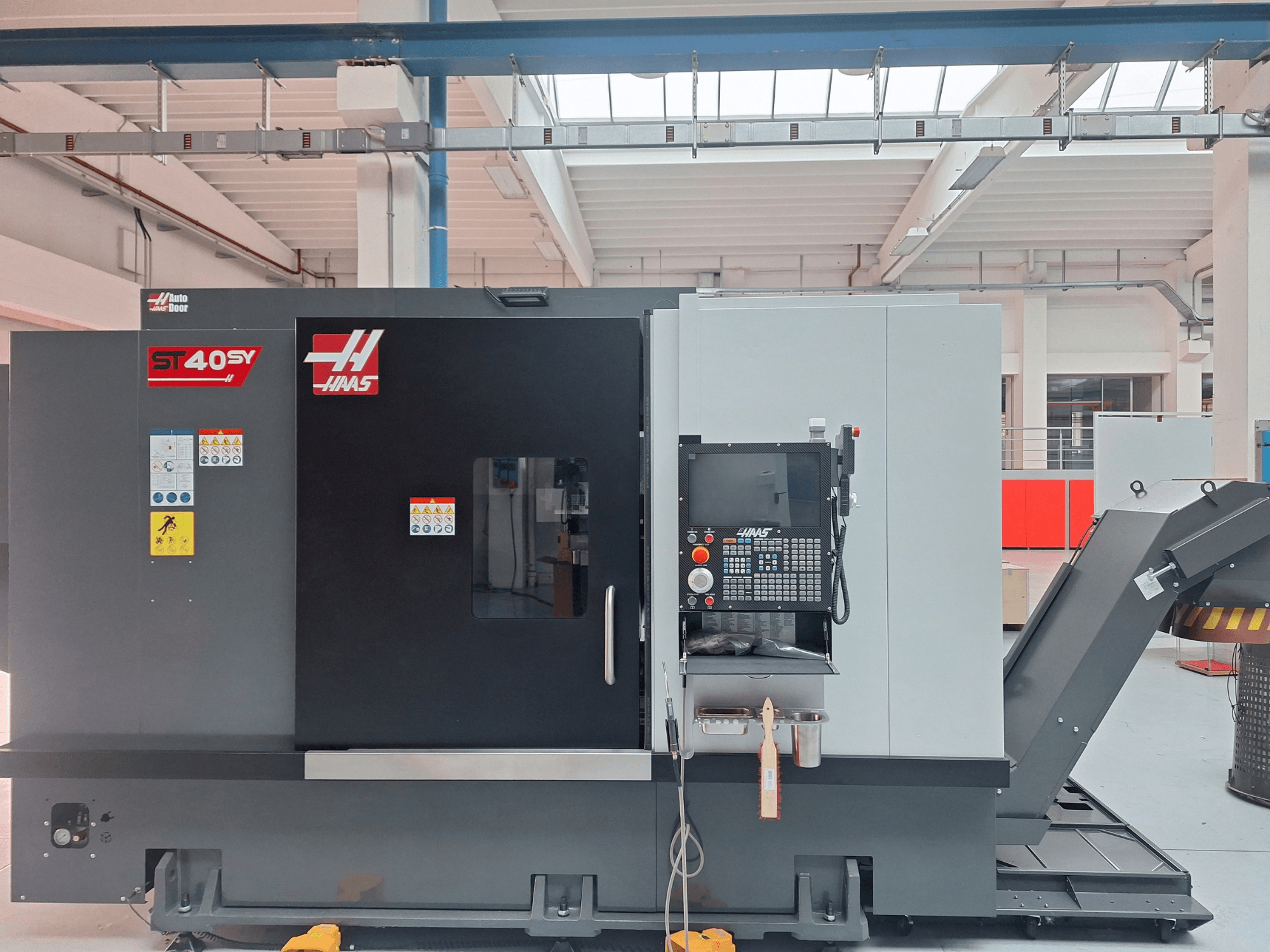 Haas ST-40SY horizontālā virpošanas mašīna, skats no sāniem, kurā redzams vadības panelis un drošības uzlīmes.