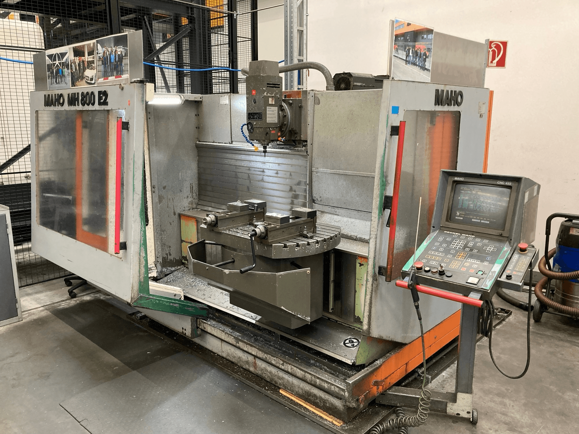 Maho MH 800 E2 CNC frēzmašīna priekšpusē ar redzamu vadības paneli, vārpstu un darbgaldu.