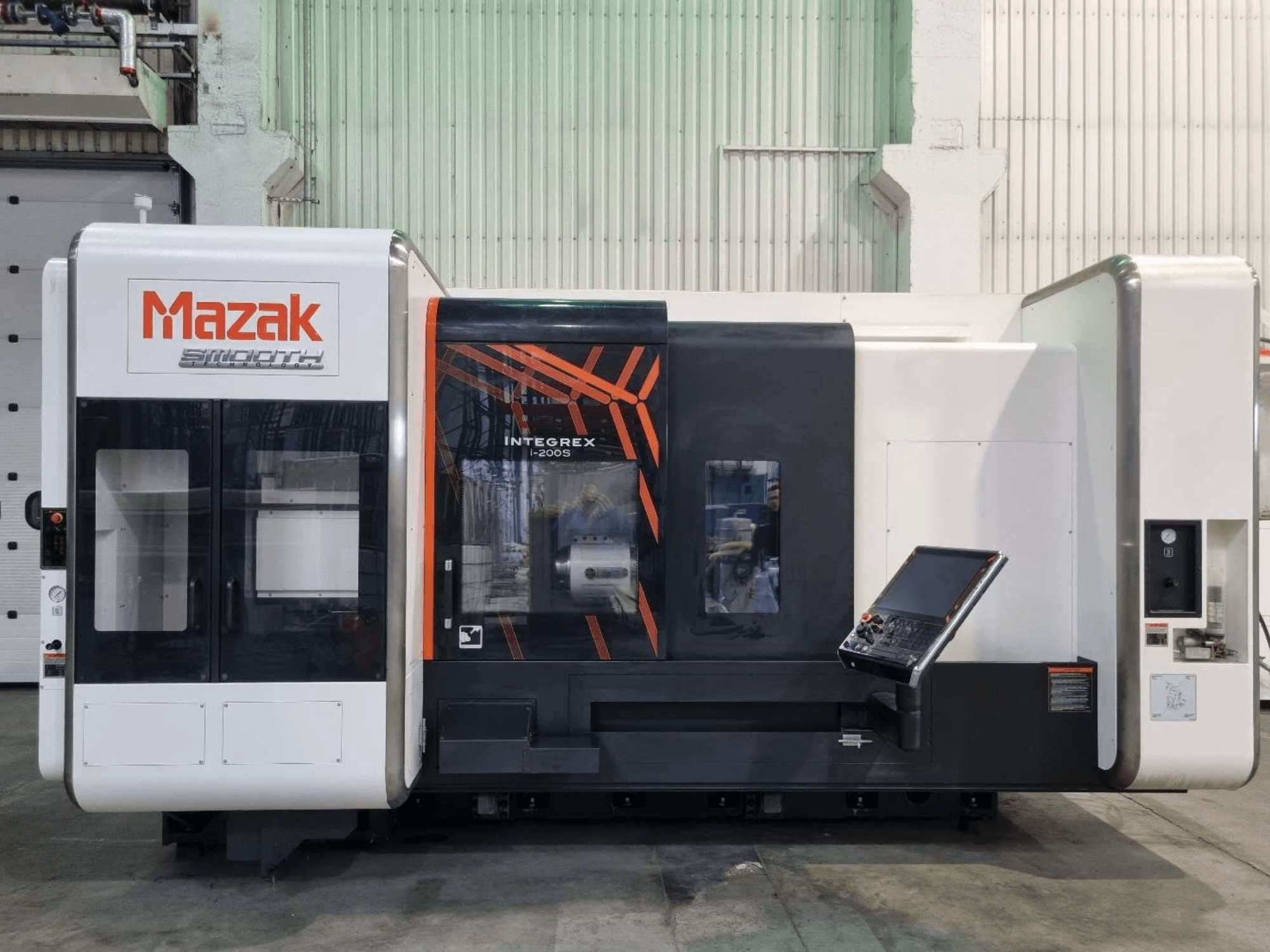Mazak INTEGREX i-200 S rotācijas frēzēšanas centrs, skats no priekšpuses, ar vadības paneli un lielu logu, kas nodrošina redzamību apstrādes zonā.