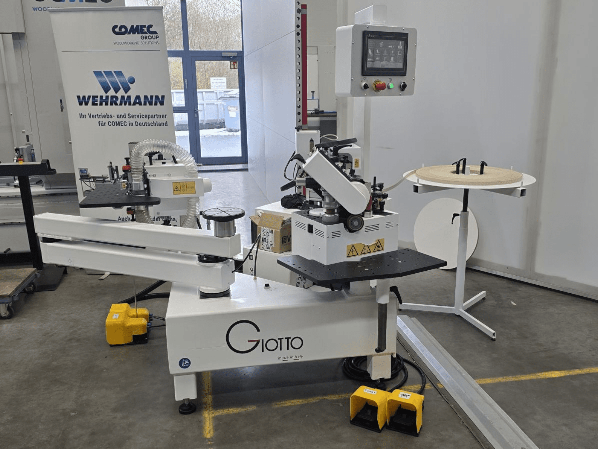 Giotto kokapstrādes darbagalds ar vadības paneli, skats no sāniem, ar kājstarpēm un rotējošu darba virsmu.