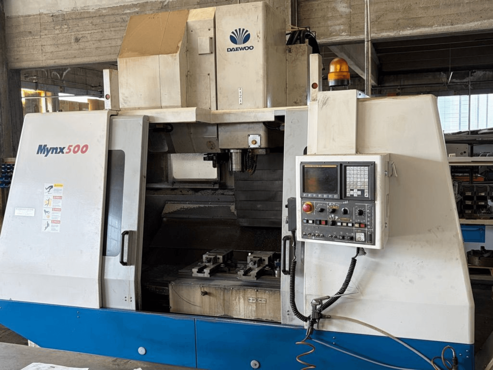 DAEWOO Mynx 500 vertikālais apstrādes centrs, redzams no priekšpuses, ar vadības paneli un instrumentu turētāju iekšpusē.