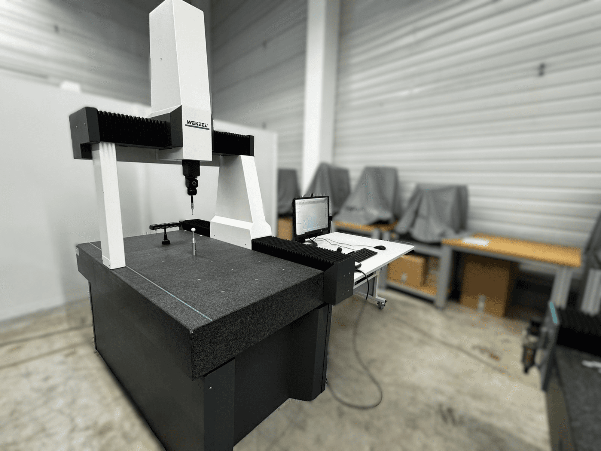 Wenzel LH 54 koordinātu mērīšanas iekārta sānu skatā ar zondi un datora saskarni uz pelēkas pamatnes.