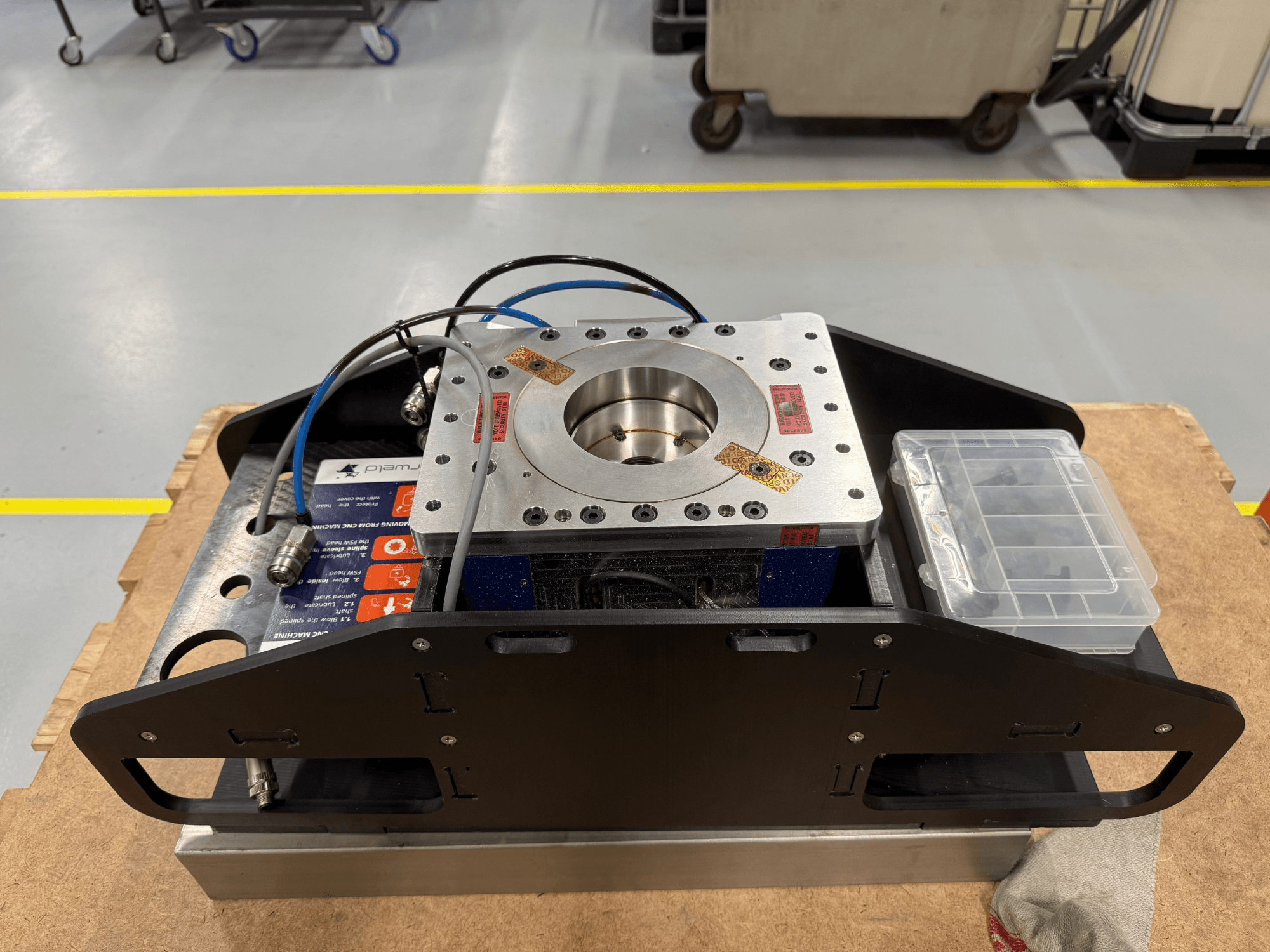 Apstrādāta metāla detaļa ar ziliem kabeļiem, piederumu korpusu un plakanu pamatni, attēlota no augšas, ideāli piemērota mehāniskiem lietojumiem.