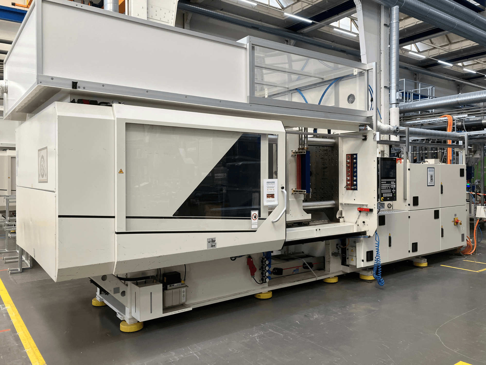 Sānu skats uz AET modeļa iesmidzināšanas formēšanas iekārtu ar vadības paneli un caurspīdīgiem vākiem rūpnieciskā vidē.