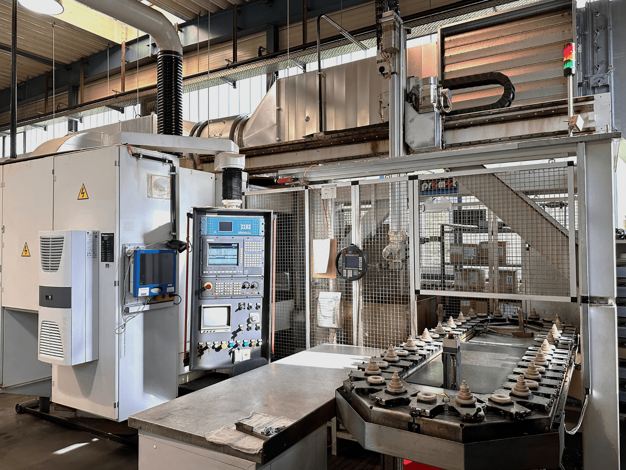 Rūpnieciskās iekārtas ar vadības paneli, dzesēšanas bloku un konveijeru. Skats no priekšpuses ar spilgtām gaismām un drošības zīmēm.