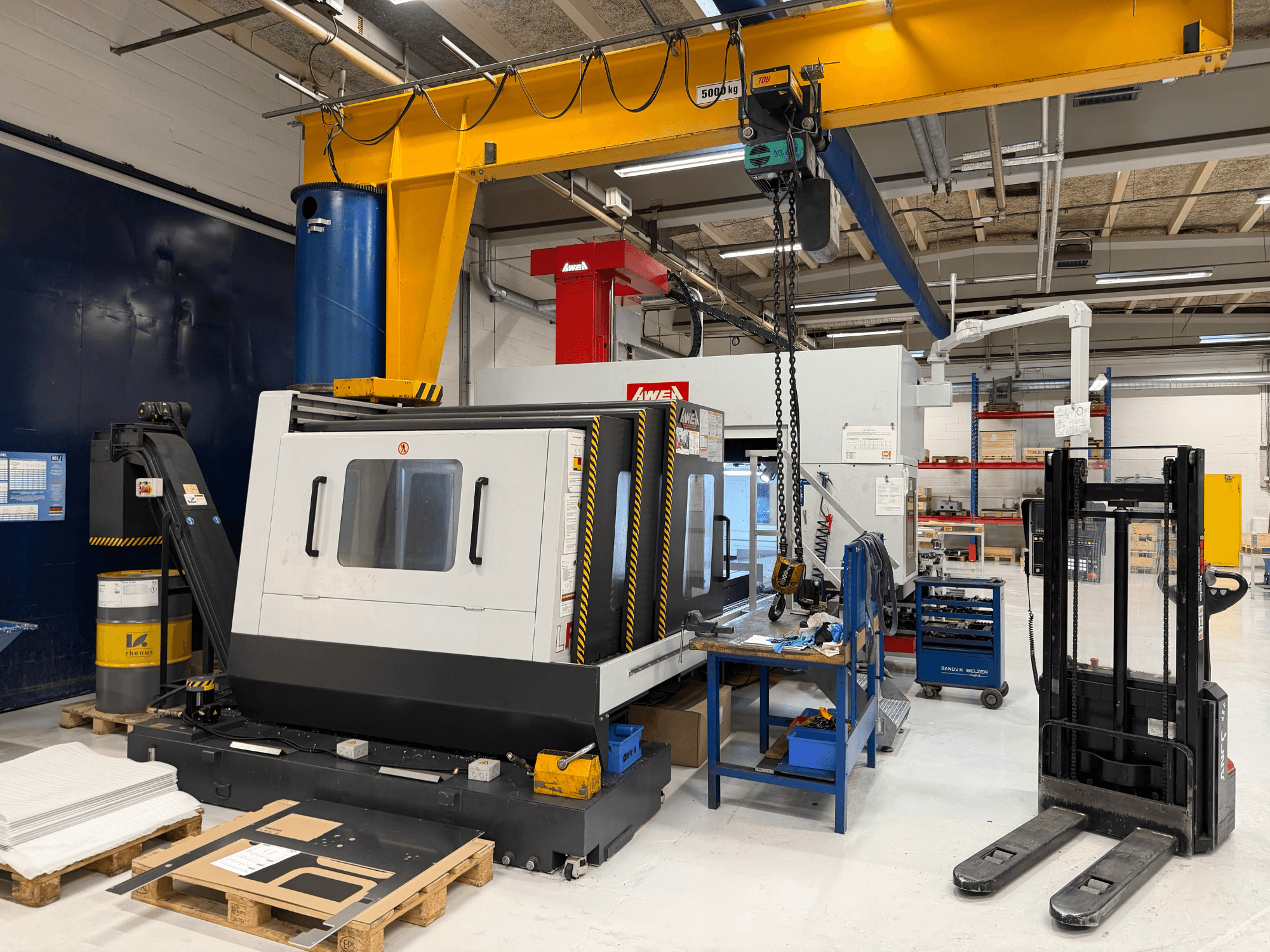 Portālfrēzmašīna AWEA LP3016YF, skats no priekšpuses, ar instrumentiem, zilo tvertni un darba vietu fonā.