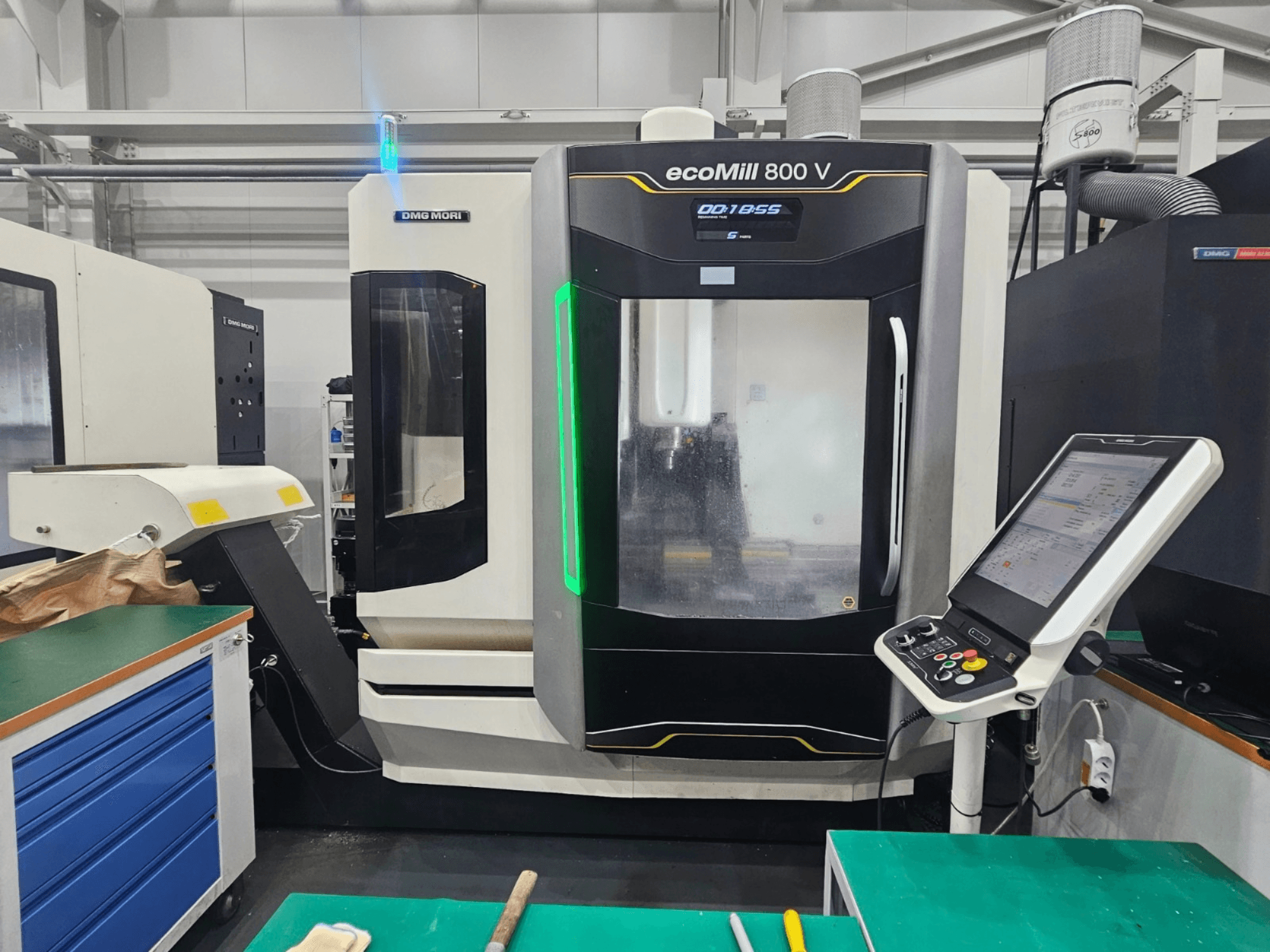 Vertikālais apstrādes centrs DMG MORI ecoMill 800 V, skats no priekšpuses, kurā redzams vadības panelis un mašīnas detaļas.