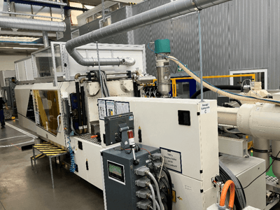 Iesmidzināšanas veidošanas iekārta, skats no priekšpuses, ar zīmola marķējumu, vadības paneli un redzamām šļūtenēm rūpnīcā.