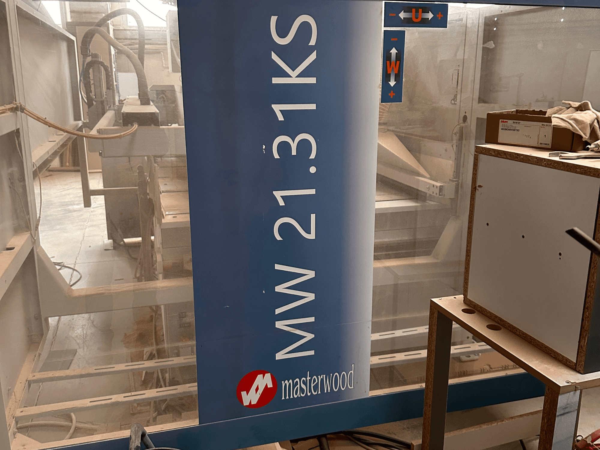 MASTERWOOD Ks 21.31 koka urbjmašīna, priekšējais skats, kurā redzamas modeļa detaļas un apkārtējā darba telpa.