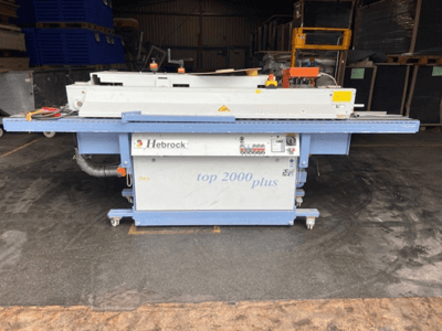 Hebrock Top 2000 Plus, skats no priekšpuses; industriālā elektriskā mašīna ar vadības paneli, riteņiem pārvietošanai un redzamām drošības uzlīmēm.