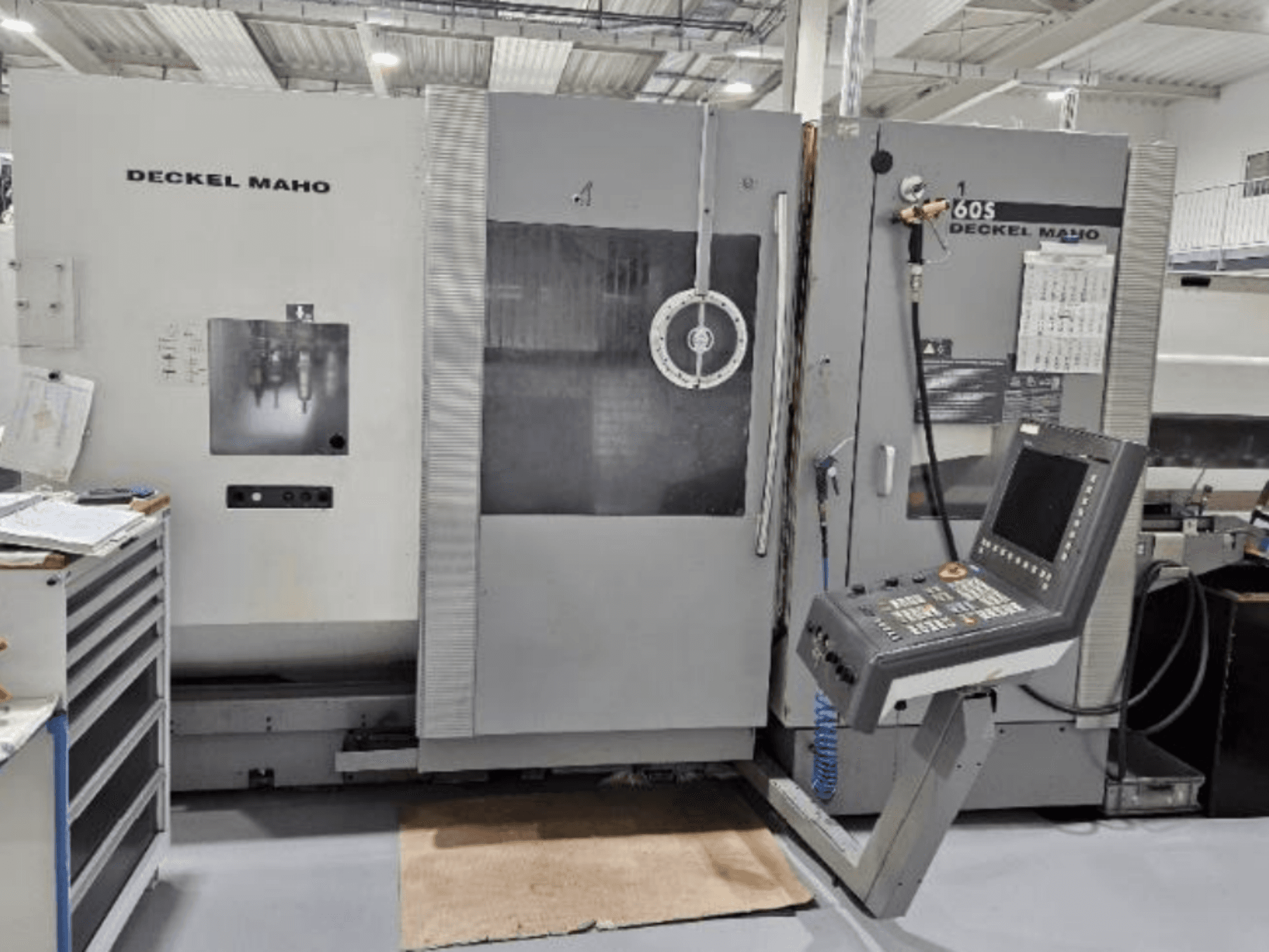 DECKEL MAHO 60S CNC mašīnas priekšējais skats ar vadības paneli, redzami instrumenti darbnīcā.