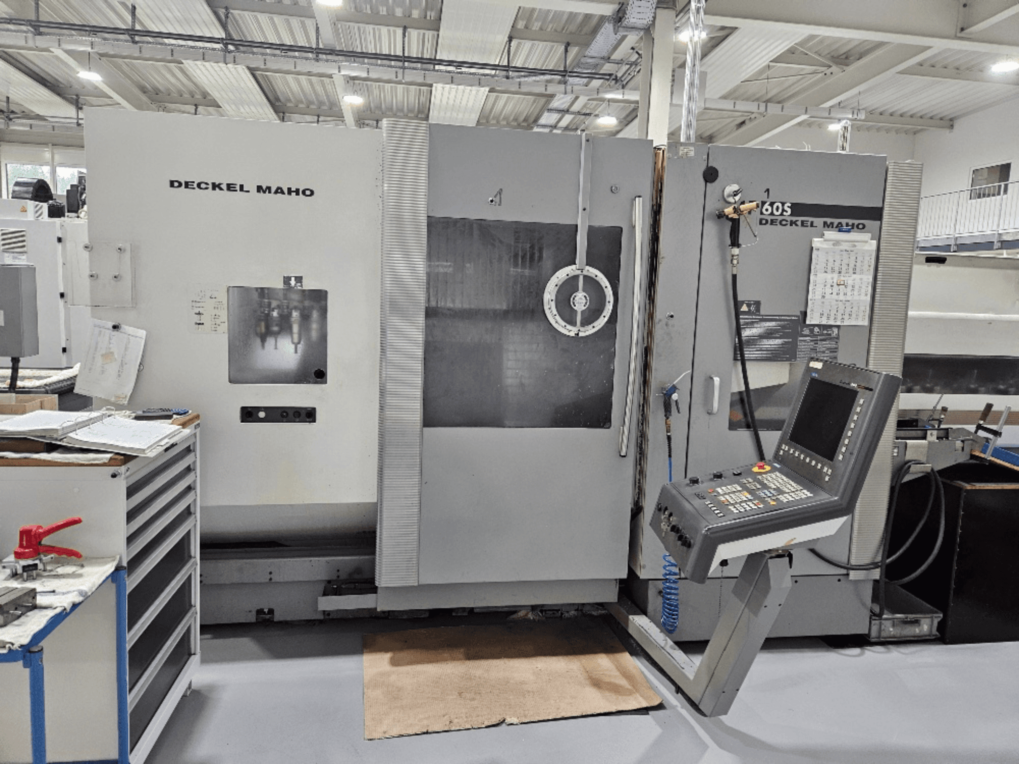 Deckel Maho 605 CNC mašīna ar vadības paneli un darbības funkcijām, skatoties no priekšpuses darbnīcā.