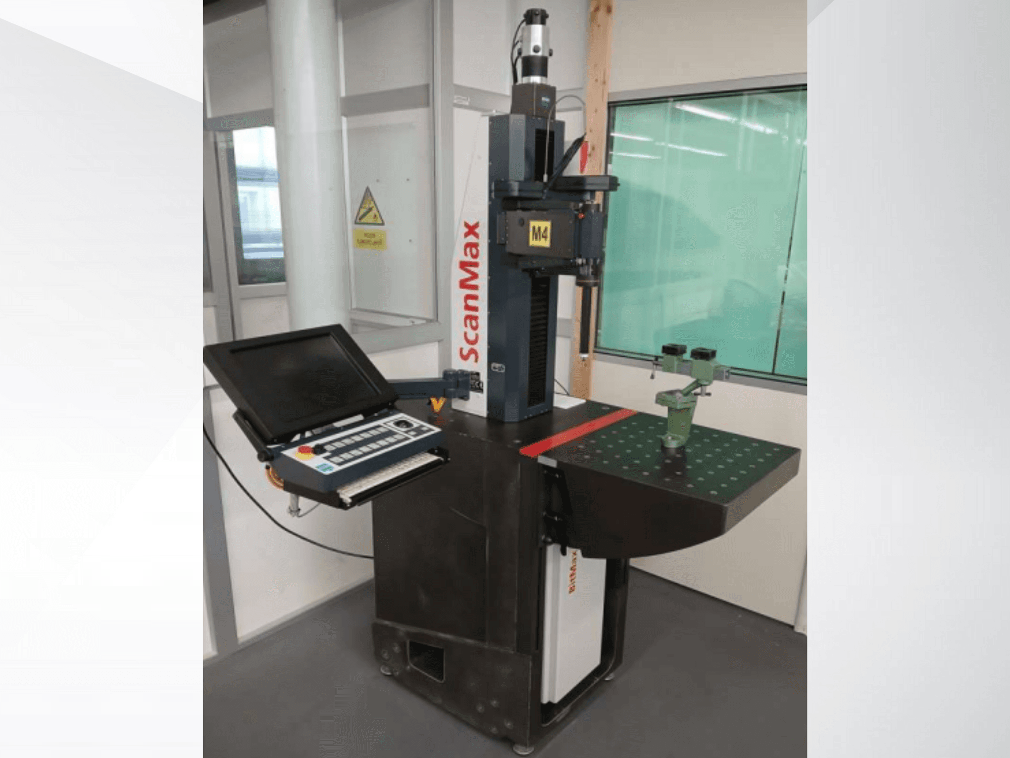 ScanMax M4 mērīšanas iekārta, priekšējais skats ar vadības paneli un zaļo kalibrēšanas stiprinājumu uz punktēta darba galda.
