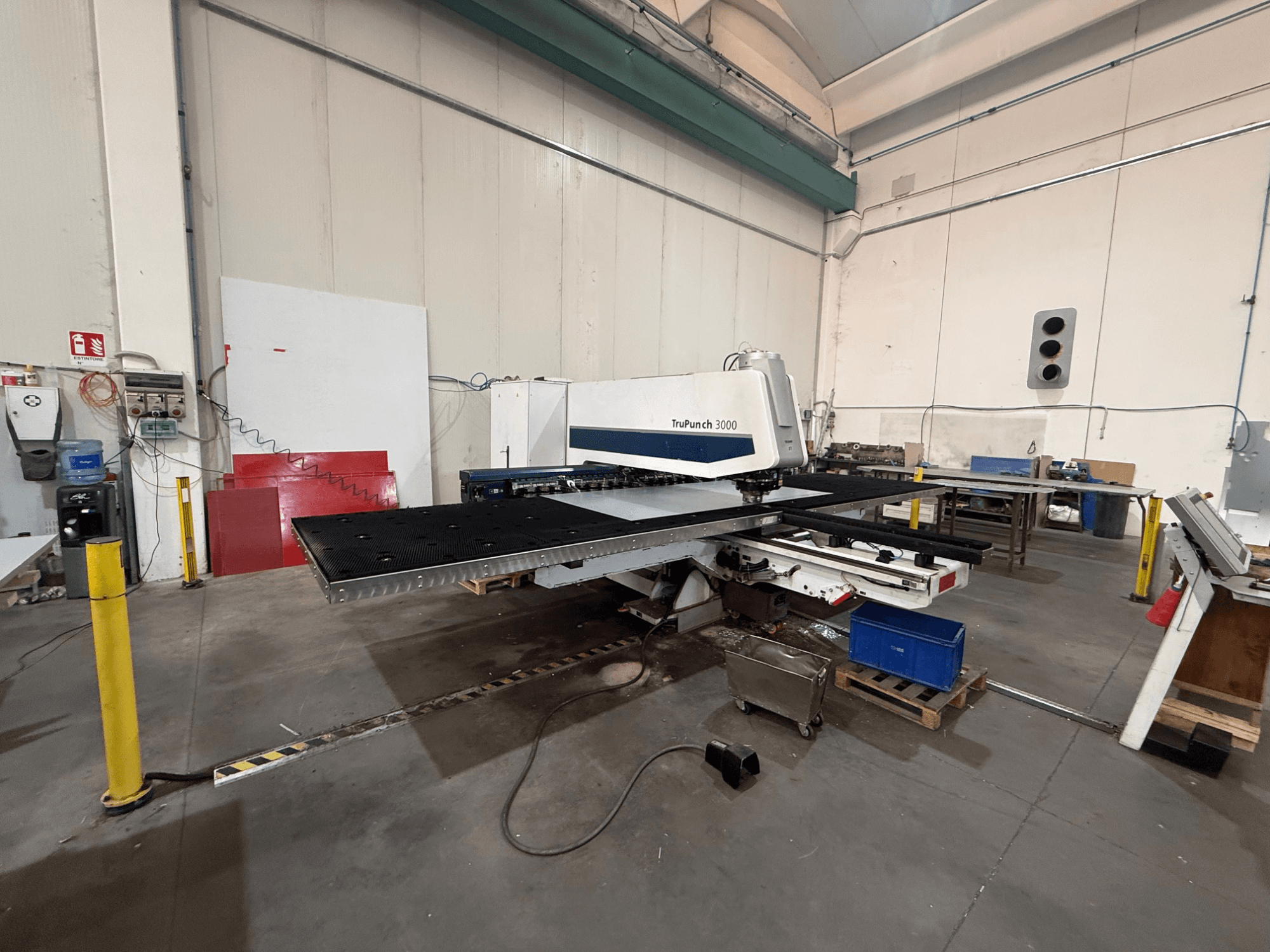 CNC perforācijas mašīna TRUMPF TruPunch 3000, skats no sāniem, kurā redzama perforācijas galviņa, liels galds un apkārtējā darbnīcas vide.