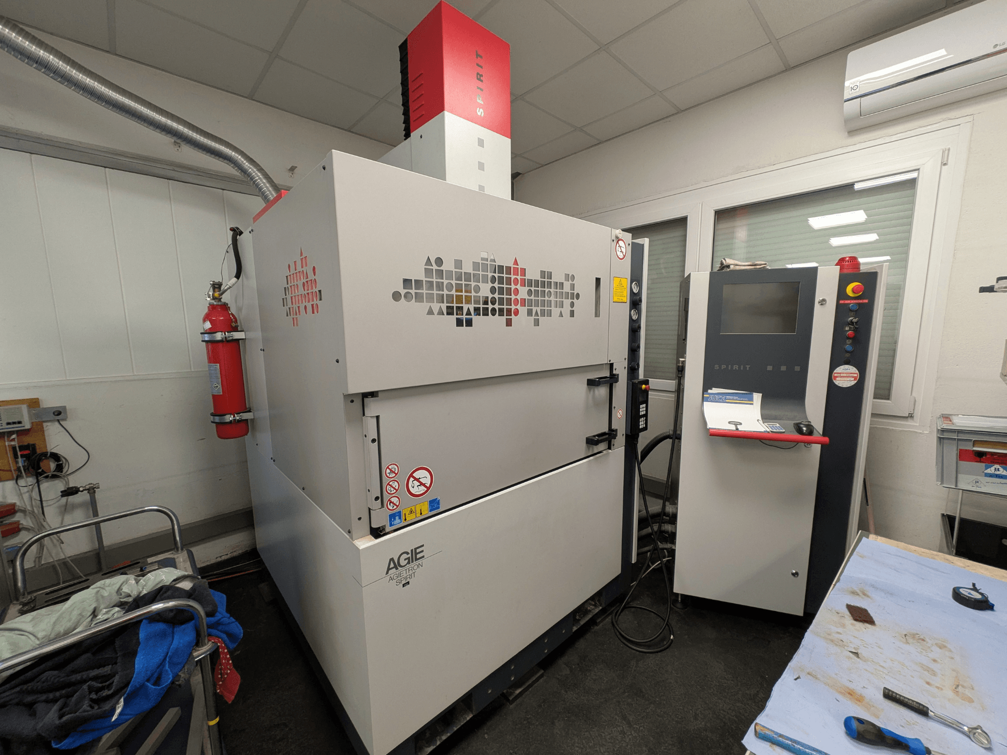 Štancēšanas EDM mašīna AGIE AGIETRON SPIRIT 3, skats no sāniem, redzams vadības panelis un ugunsdzēšamais aparāts.