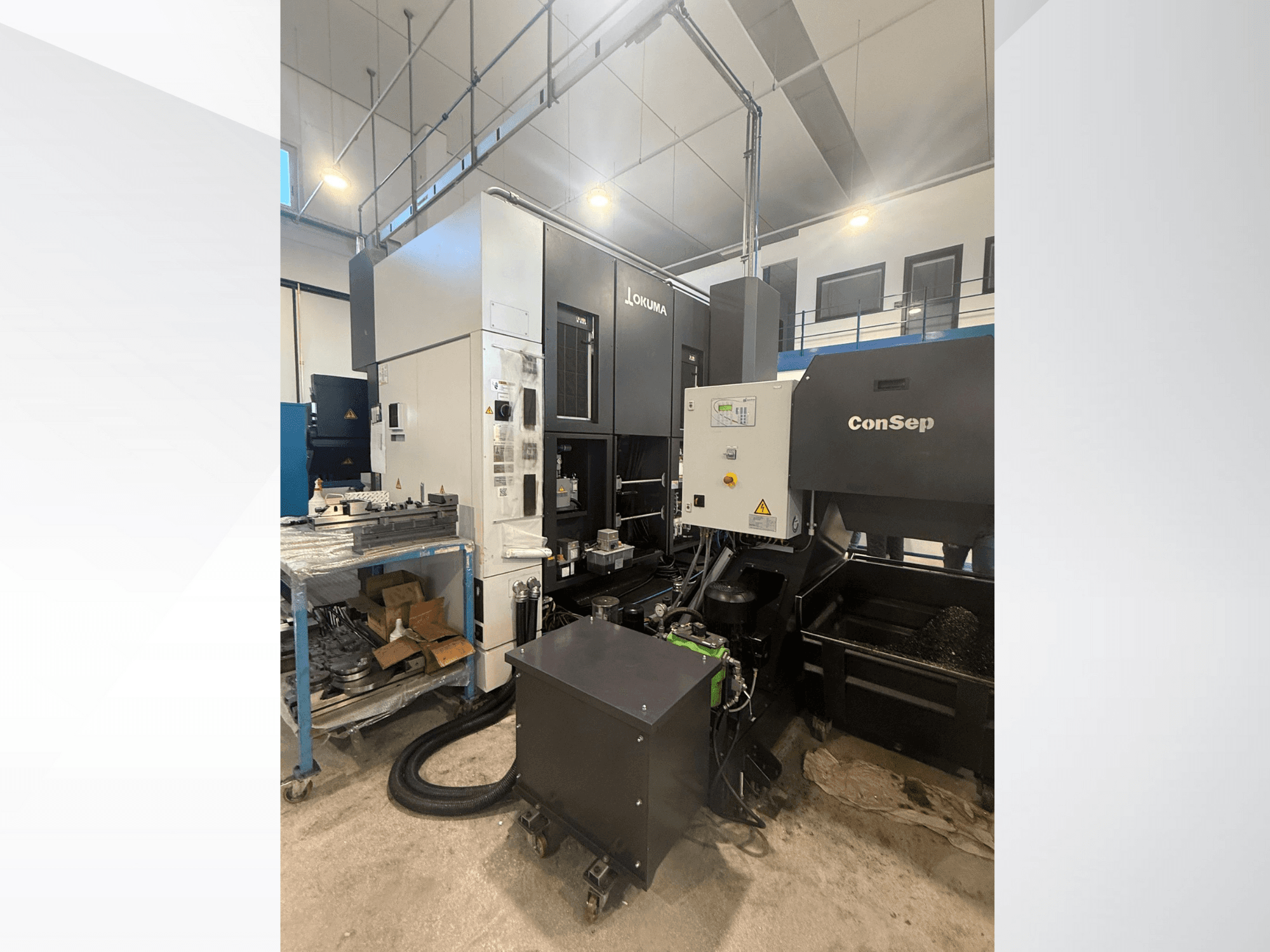 Okuma apstrādes centrs ar ConSep iekārtu, skats no sāniem, vadības ierīču un rūpniecisko iestatījumu attēls, ieskaitot metāla skaidu tvertni.