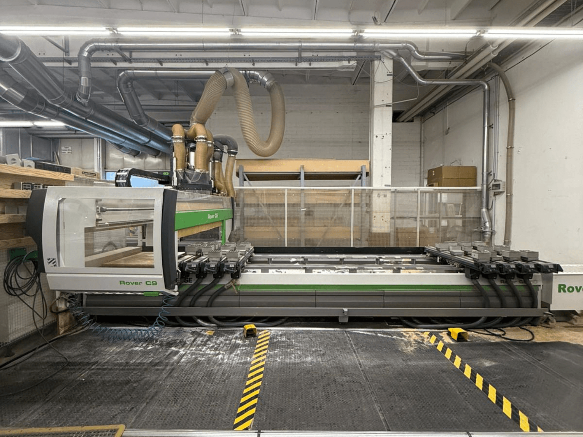 Rover C9 CNC darbnīcā, skats no priekšpuses, ar vairākām griešanas galviņām un redzamu putekļu nosūces sistēmu.
